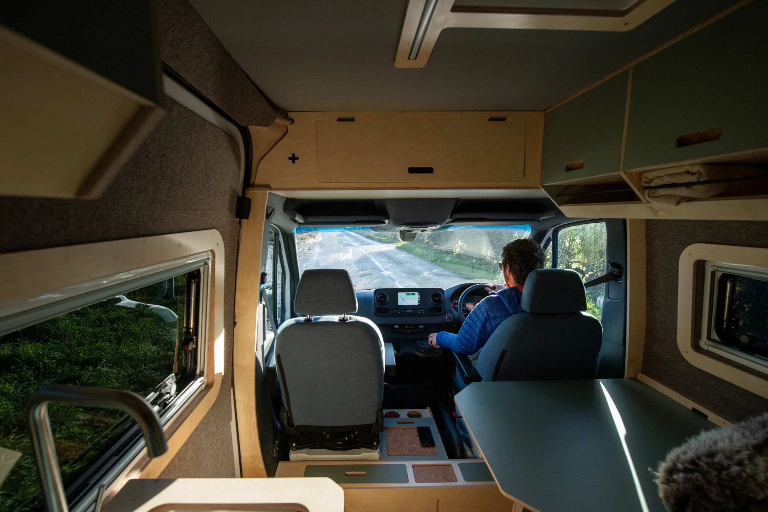 View from the living area of a Fern campervan while driving, illustrating how the onboard batteries recharge on the move, from solar, or via shore power for long journeys.