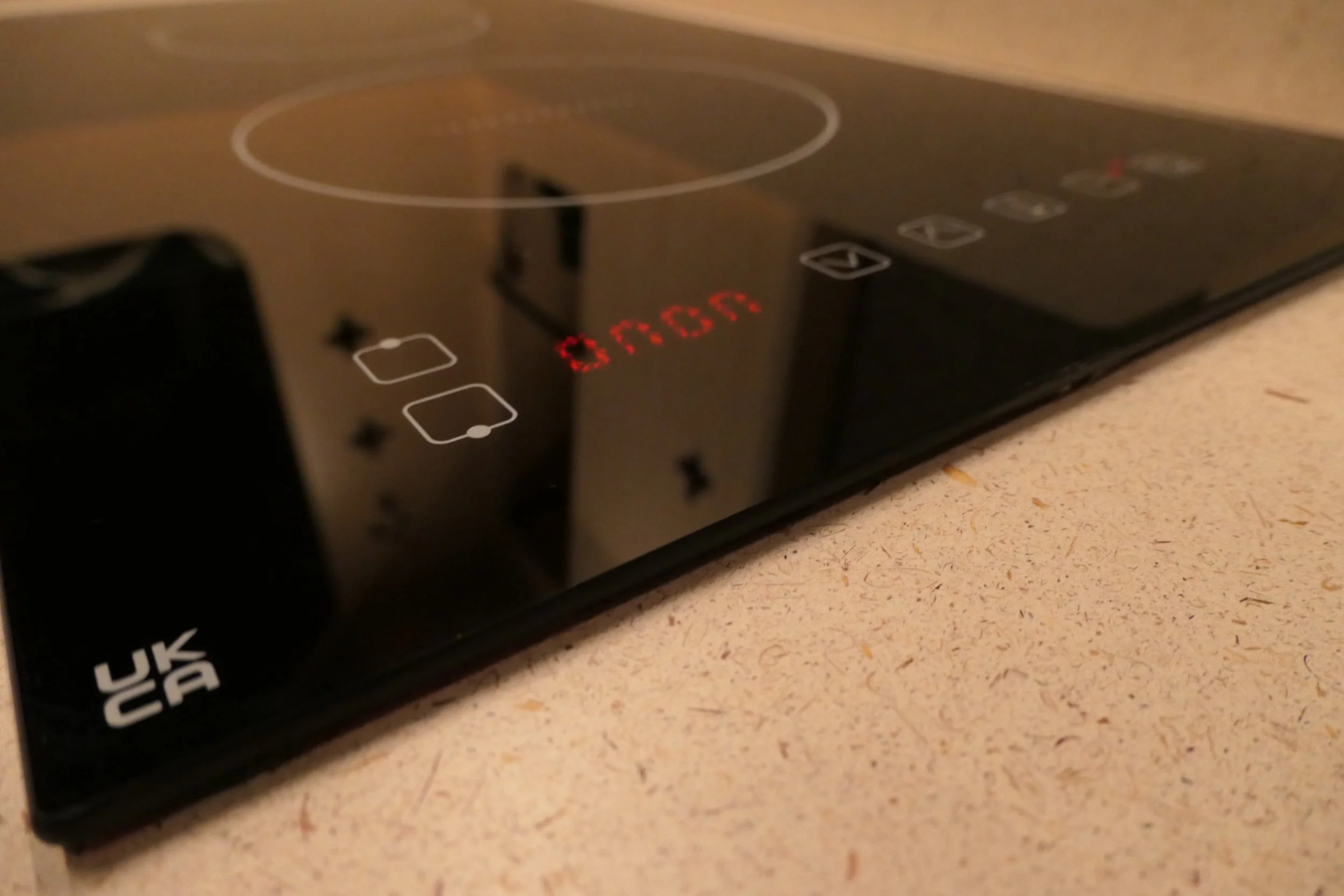 Black glass induction hob in the Fern campervan kitchen, powered by the electrical system for safe, gas-free cooking on the road.