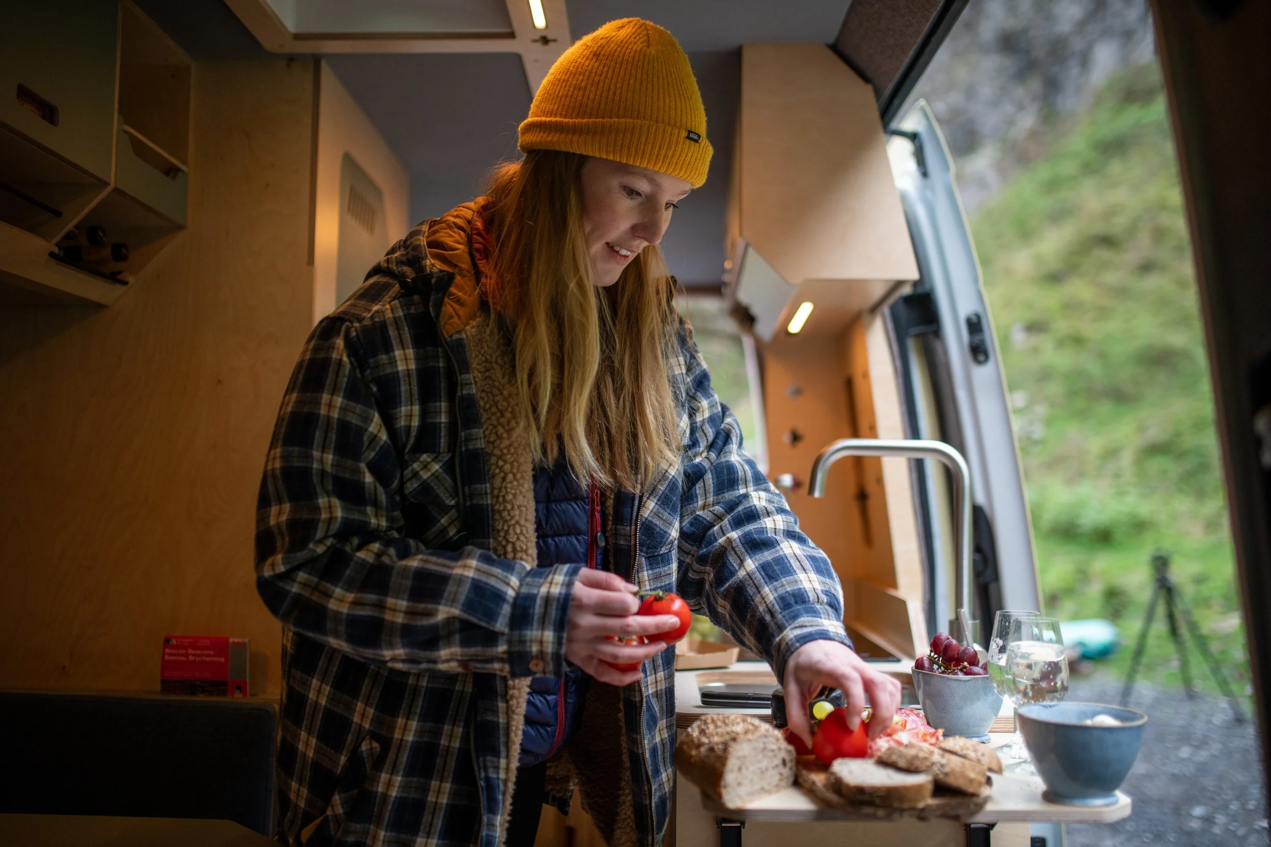 Person preparing fresh ingredients in the kitchen area of a Fern campervan, showing how the van suits travellers who love to cook well on the road.