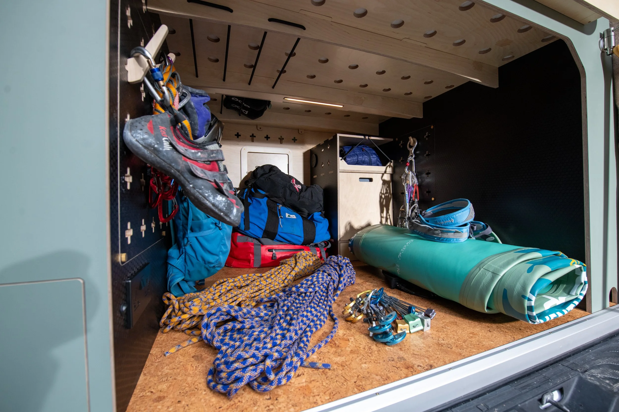 Fern campervan garage storage packed with climbing ropes, pads, and bags, using modular storage panels to keep organised.