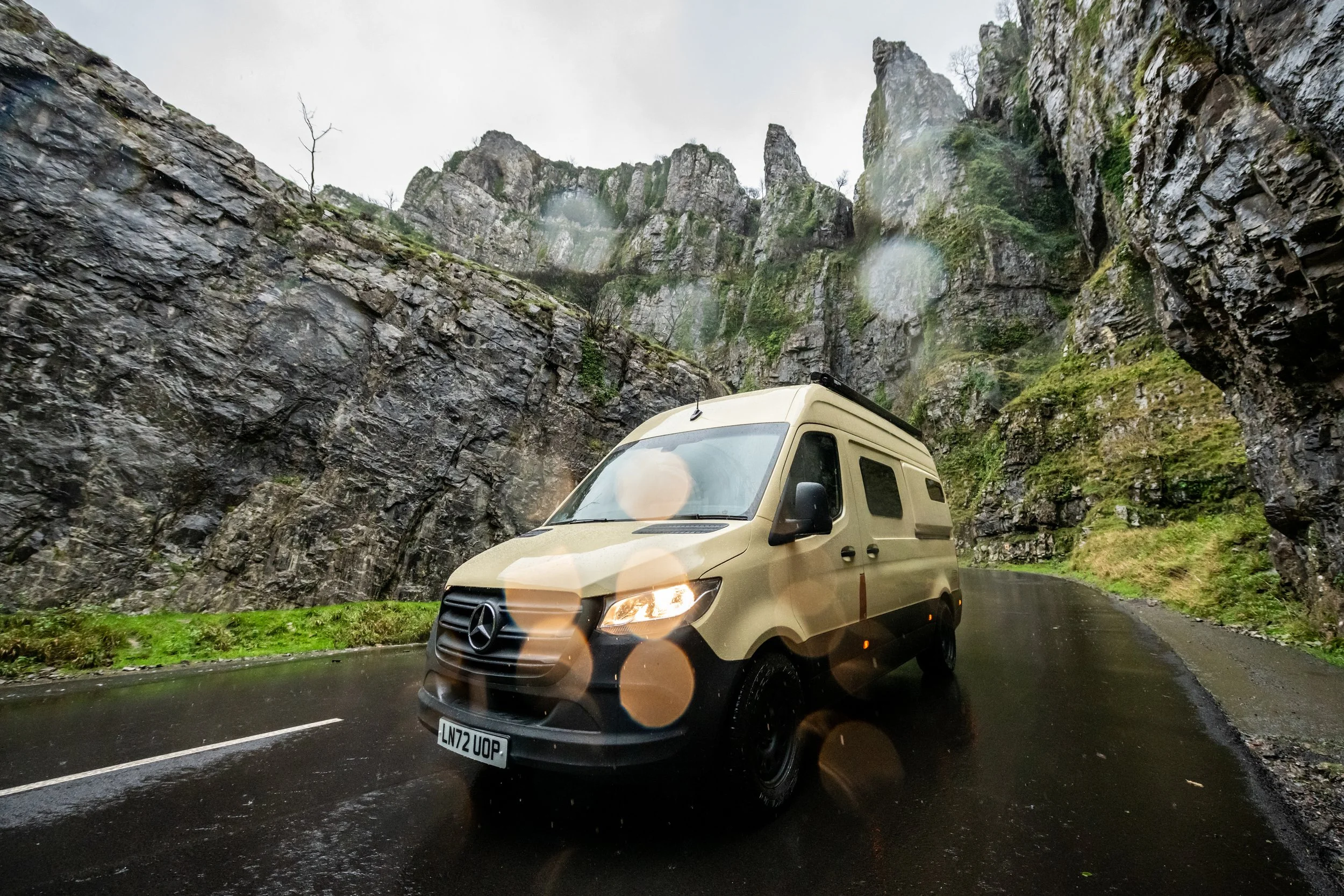 Fern campervan driving through a steep-sided gorge on a wet winter day, demonstrating confident all-weather touring.