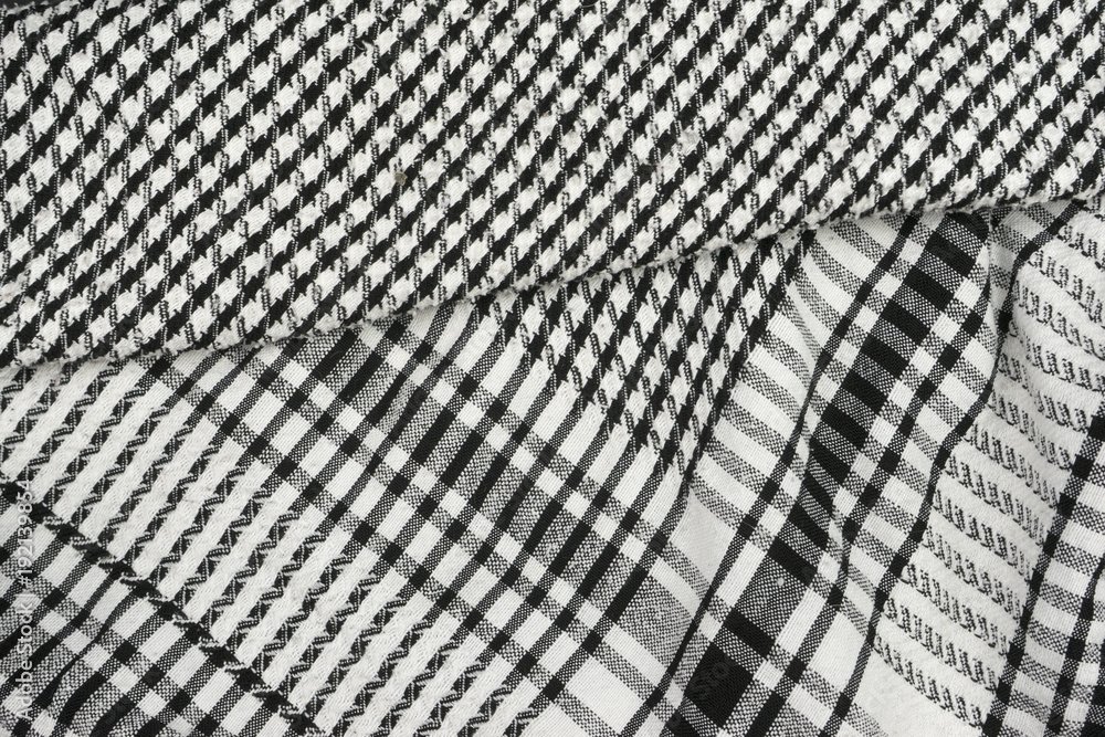 Close-up of folded black-and-white houndstooth and plaid fabric textiles.