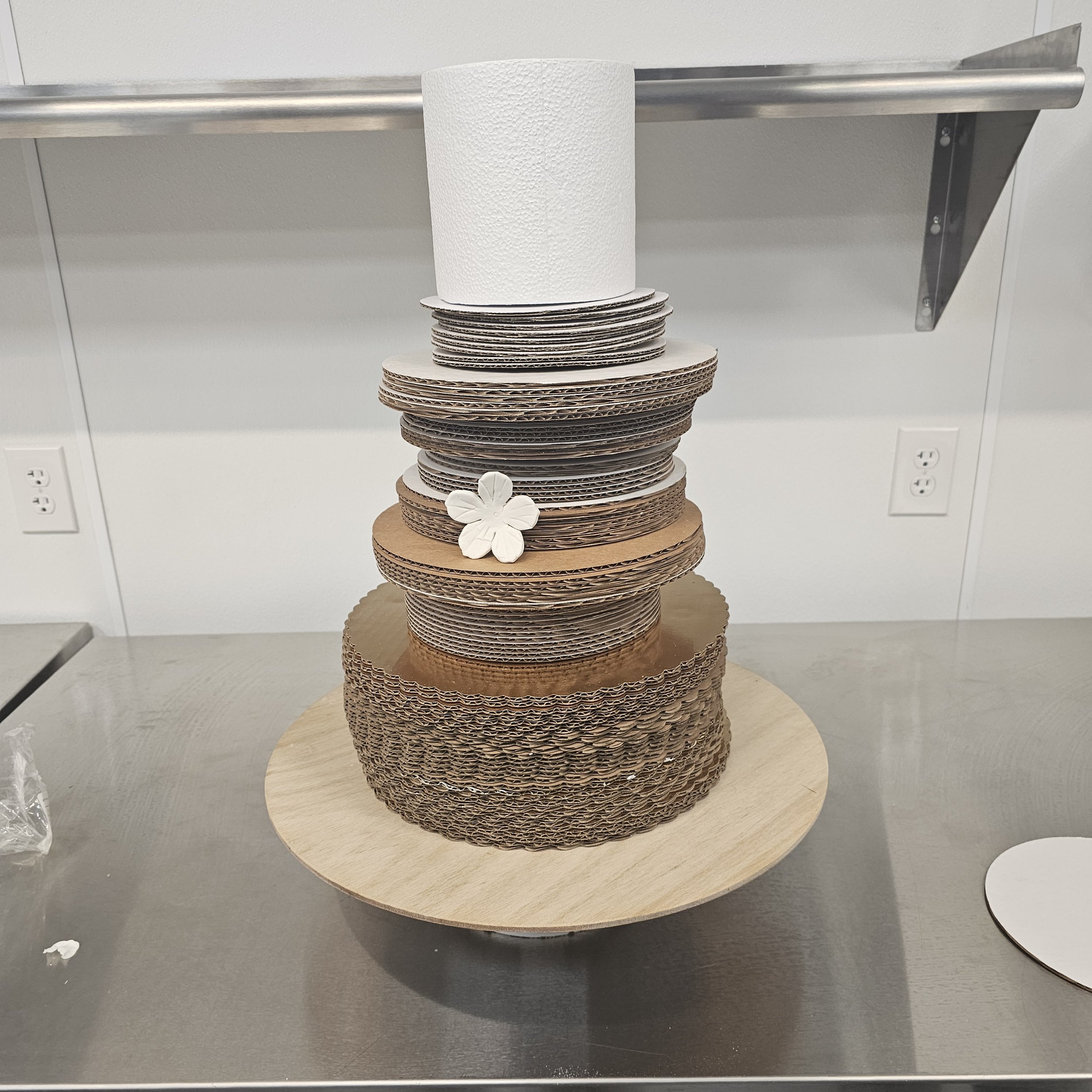 Three-tier pink birthday cake with M Mouse theme, featuring M Mouse faces with pink polka dot bows and white polka dots. The cake has decorations with the name 'KLEAH' in pink letters.