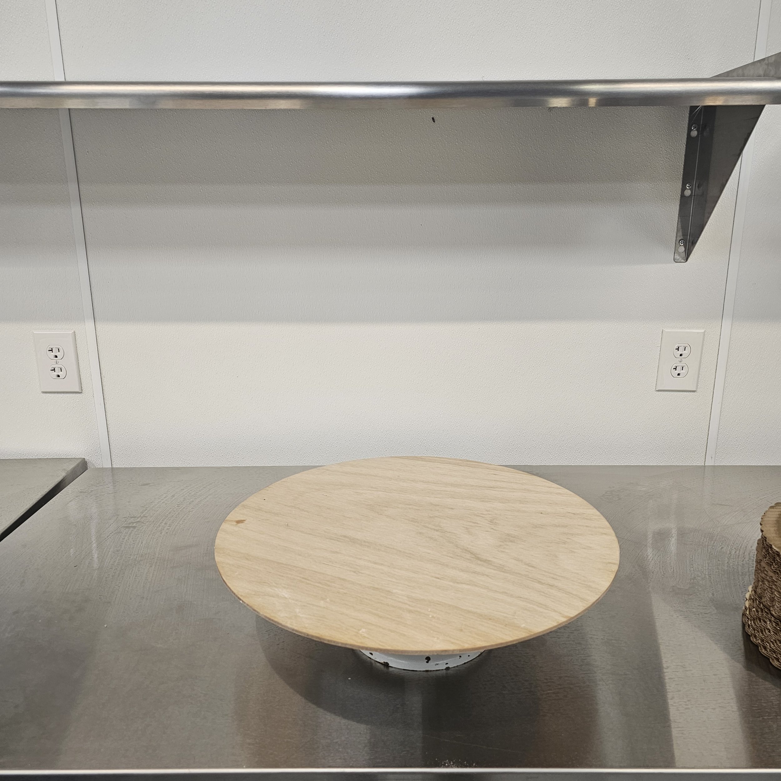 Pink fondant round cake decorated with yellow and pink frosting flowers, with actual china tea cup on top and a fondanr clock face on the front, set against a pink background.
