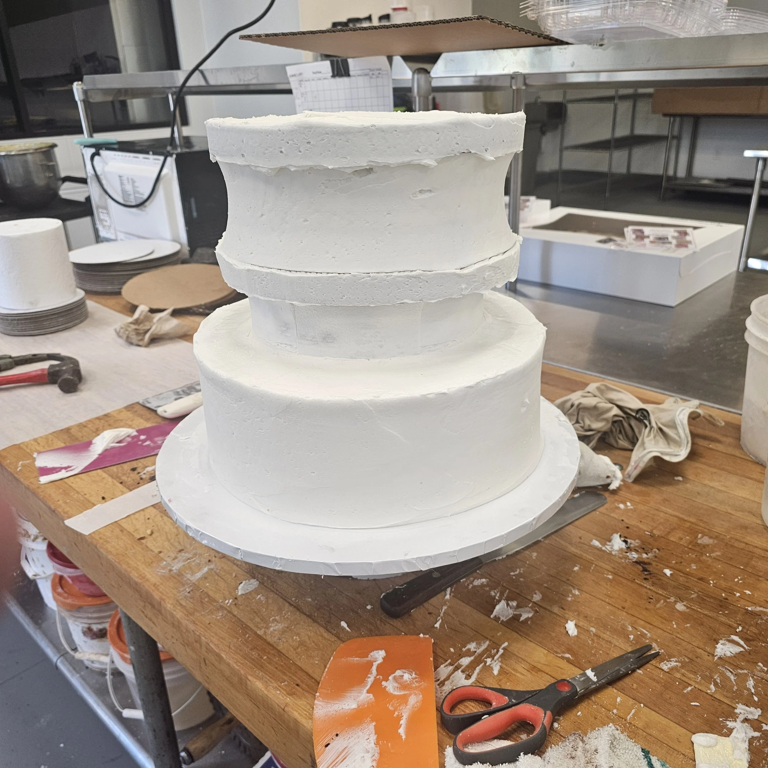 A two-tier birthday cake featuring a Tiana design. The top tier has an edible image of Tiana in a green gown, and the bottom tier is decorated with green and white icing with text that reads "Happy 6th Birthday TONI". The cake is decorated with piped icing and small pearl-like accents.