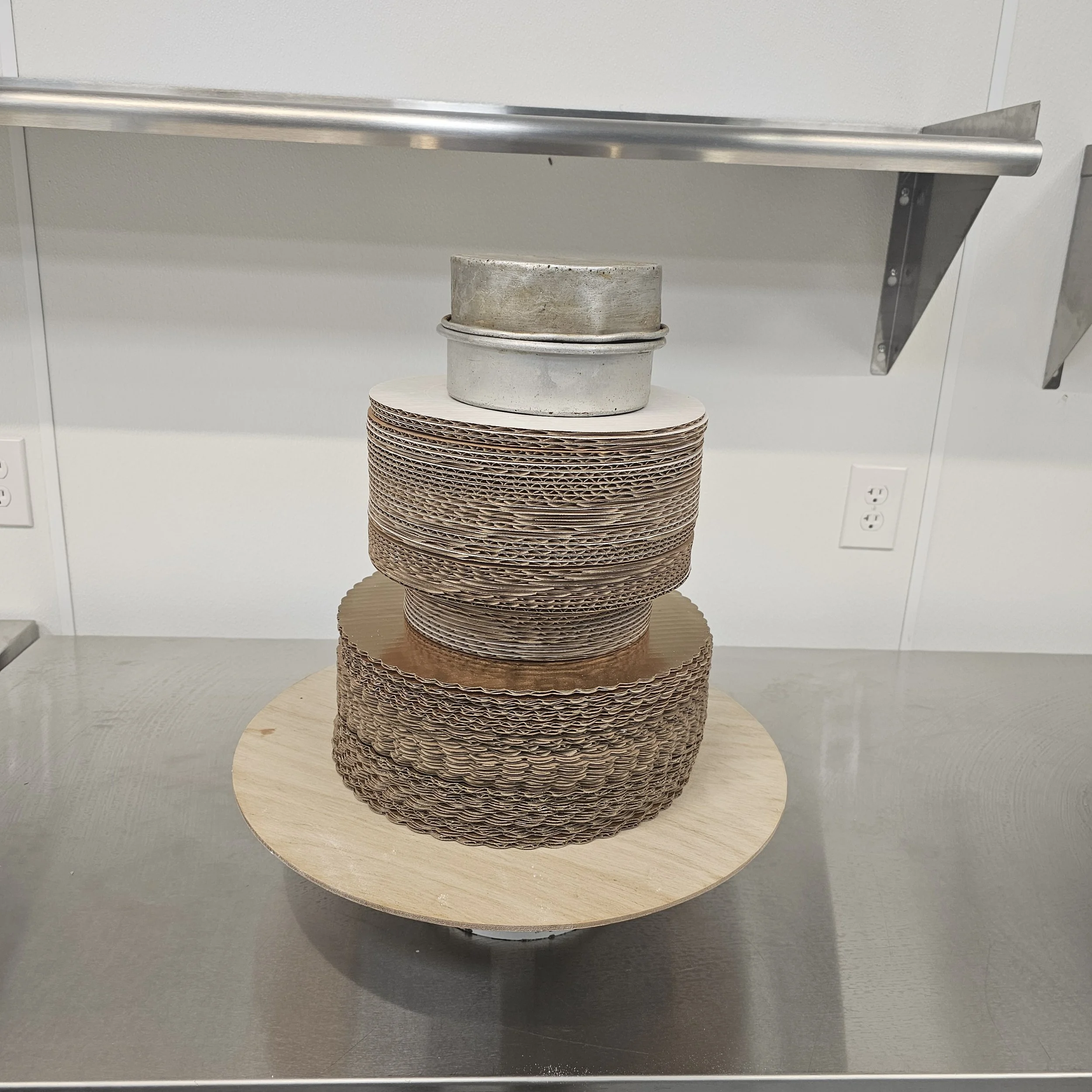 Cake with Kentucky Wildcats logo and mascot decorations, featuring blue and white frosting with blue balls and ribbon, displayed on a silver stand.