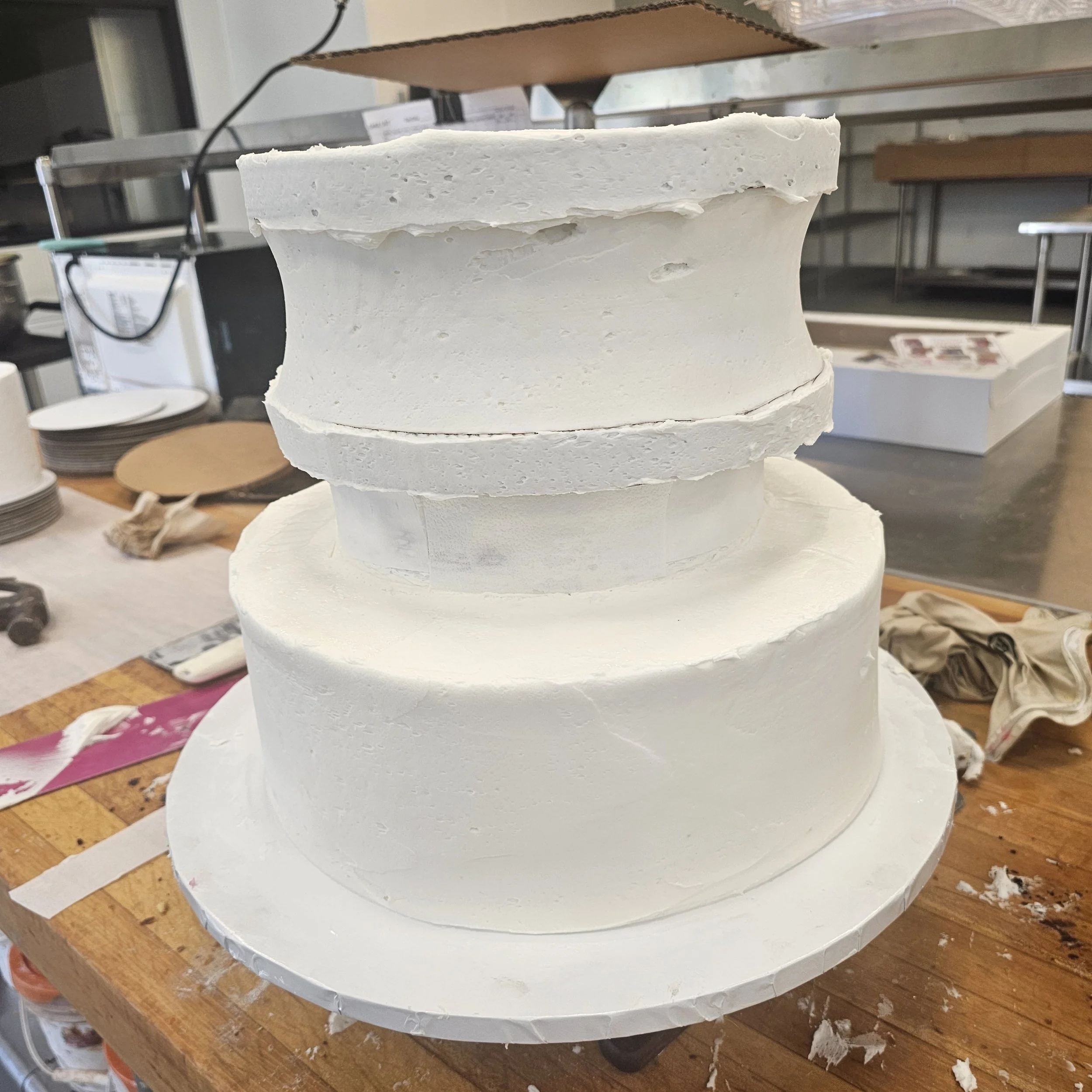 Pink birthday cake with white drip icing, pink and white swirls, and a pink heart with the name Malaiyah, topped with two pink number one candles.