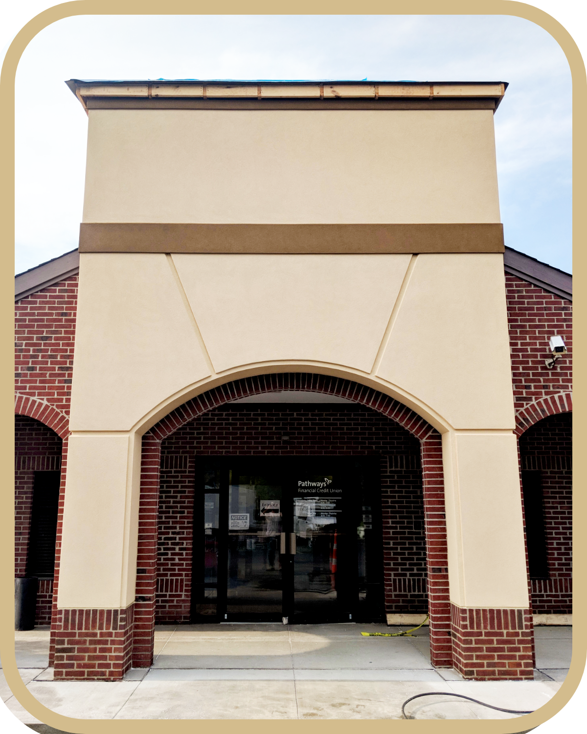 Front view of a commercial building with brick and beige stucco facade, featuring an arched entrance and glass doors for Pathways Financial Credit Union.