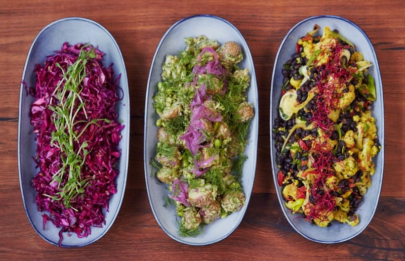 Tre fade med rødkål, salat og krydrede grøntsager – farverig og varieret catering fra Fika.