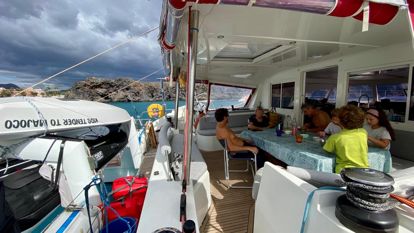 Groupe de personnes suspendues par les jambes sous un ponton de bateau en mer au coucher du soleil.