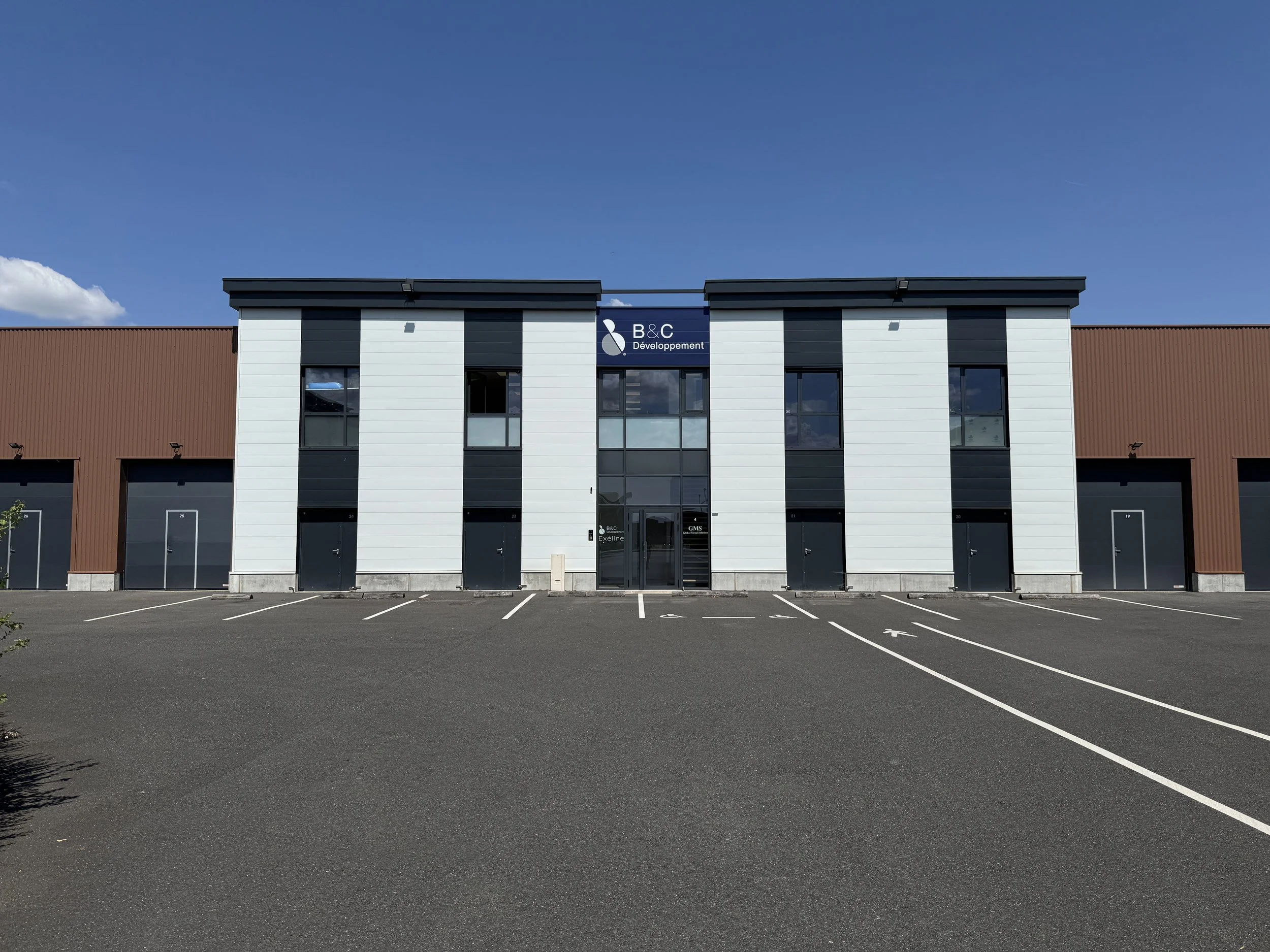 Bâtiment moderne avec un parking vide devant, enseigne 'B&C Développement' au centre supérieur, localisé à Val d'europe.