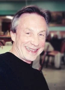 Smiling man with gray hair in indoor setting.