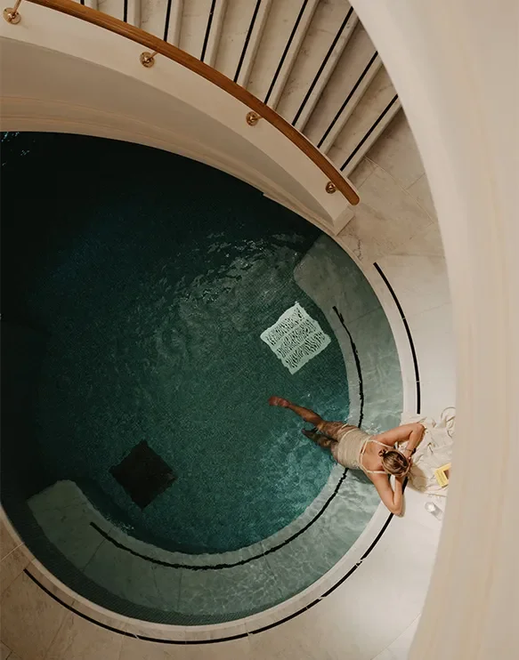 Frau steht in einem kreisförmigen, kleinen Pool im Hotelzimmer, mit Blick von oben, entspannter Atmosphäre.
