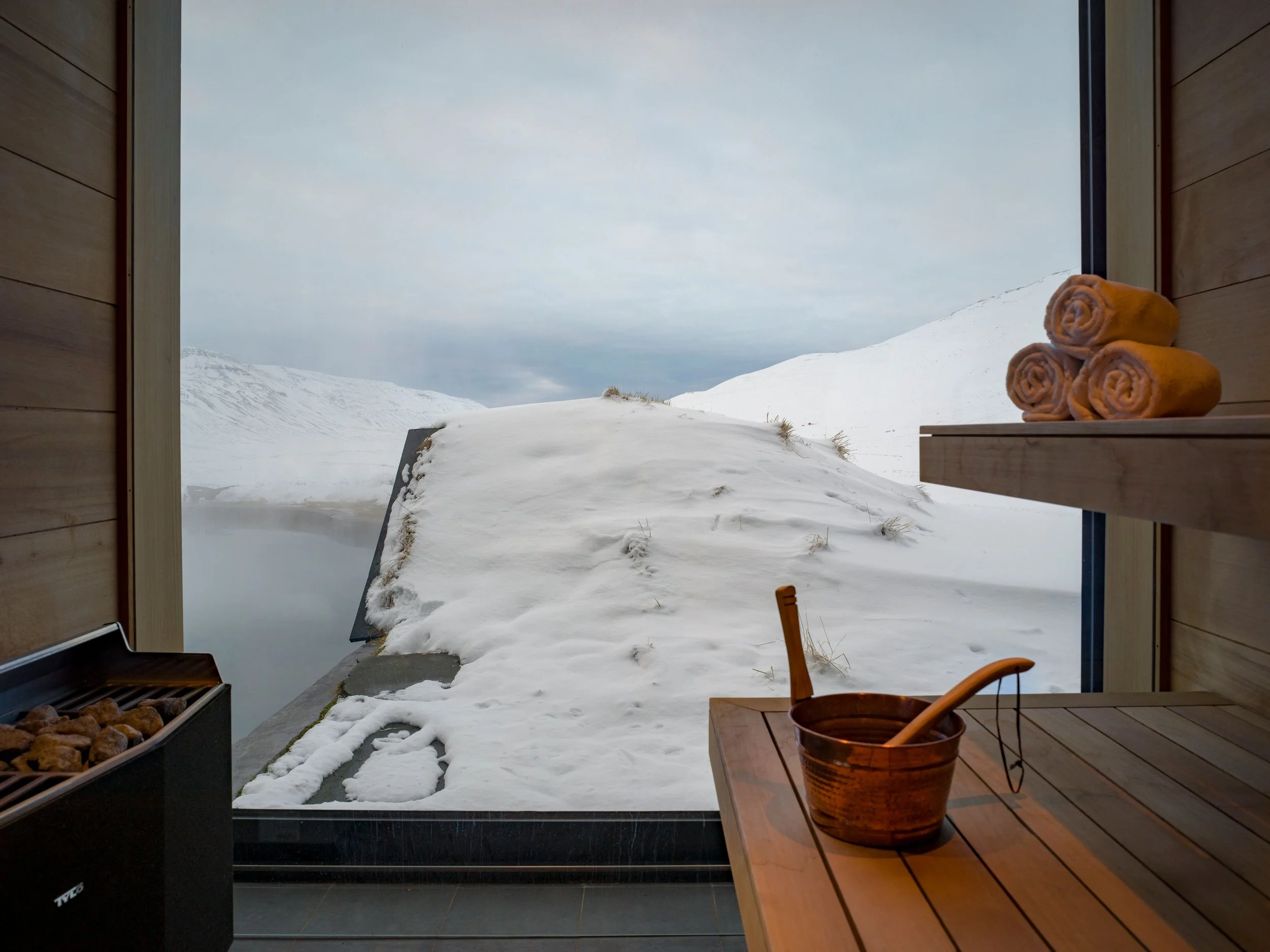 Innenraum eines Saunaraums mit Blick auf verschneite Berge und Fenster