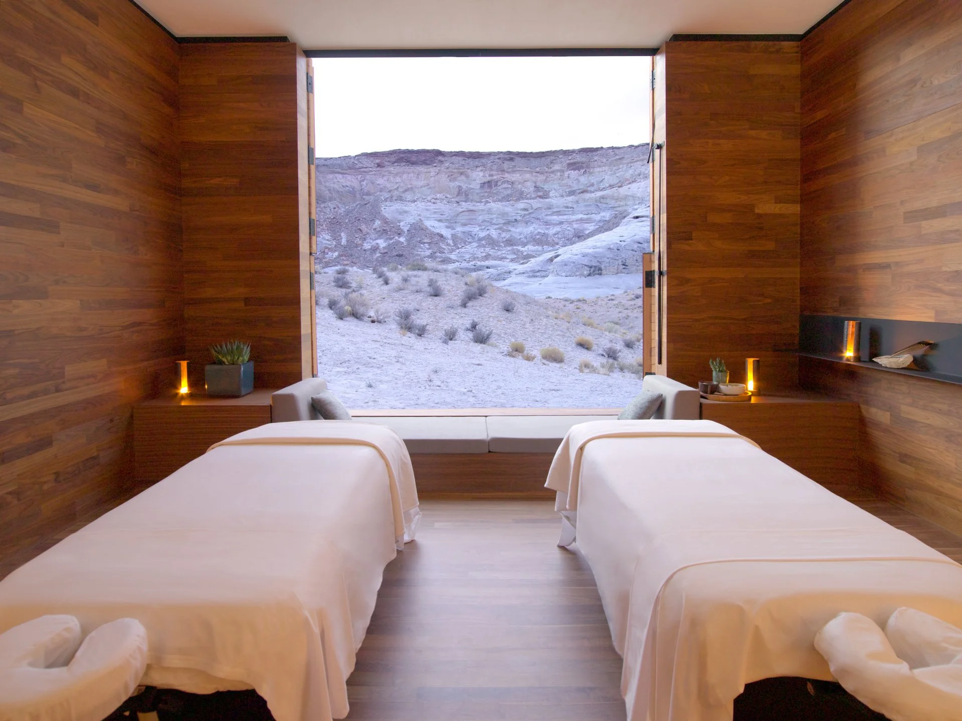 Schlafzimmer mit zwei Behandlungsbetten in Naturumgebung mit großer Fensterfront und Blick auf eine Wüstenlandschaft.
