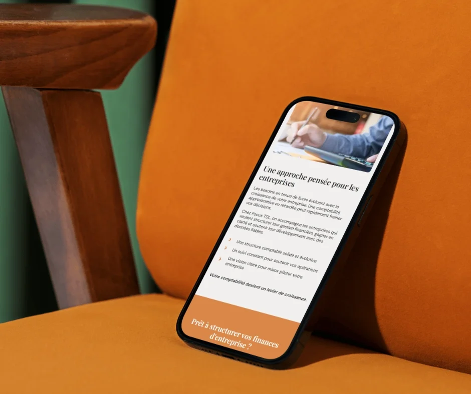 Un smartphone posé sur une chaise orange affichant une page web avec un titre en français, texte descriptif et une image d'une personne en costume écrivant.
