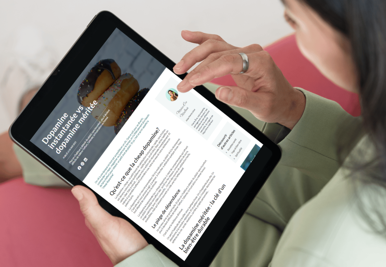 Une personne tenant une tablette affichant un article sur la dopamine et l'addiction, avec une photo de donuts en haut de l'écran.