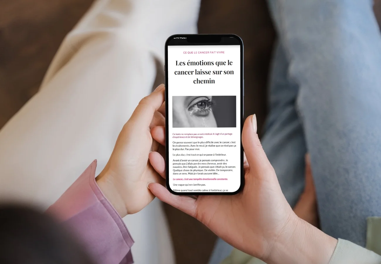 Une personne tient un smartphone affichant un article sur le cancer et ses émotions associées, avec une image d'un œil pleurant.