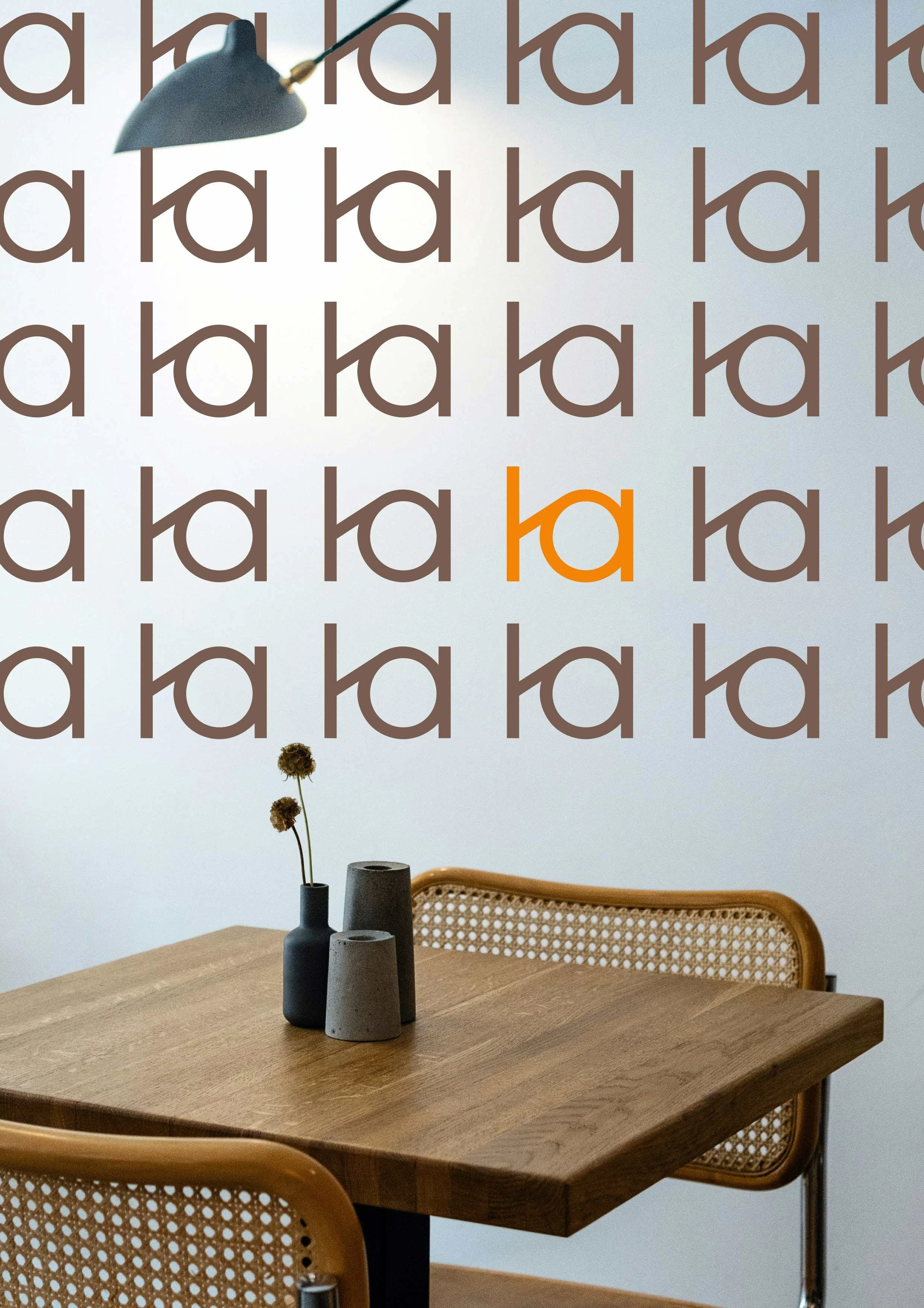 Motif monogramme d'une entreprise d'architecture d'intérieur. Avec un fond photo représentant une table en bois avec trois vases gris foncé, une chaise en rotin.