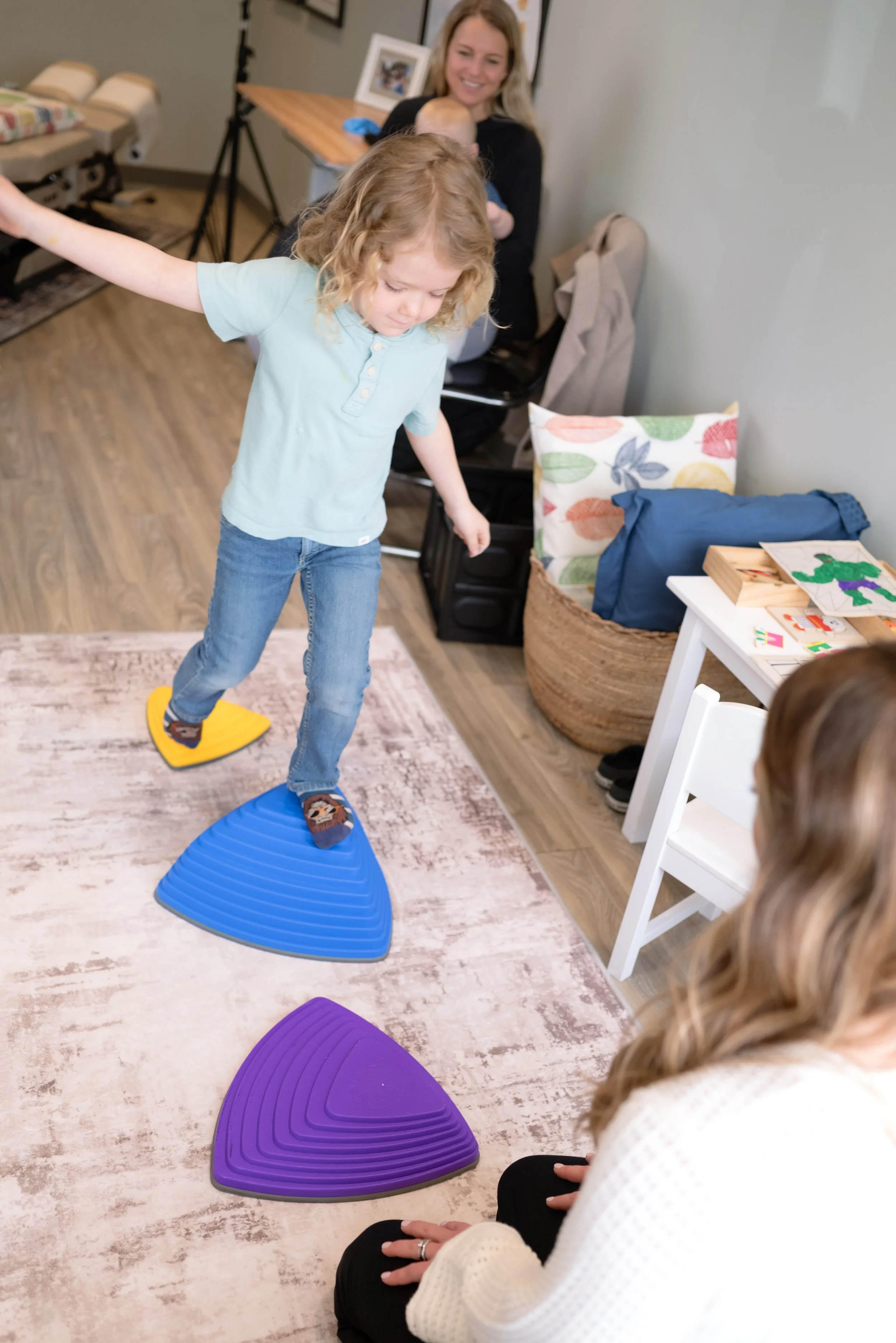 Child practicing motor coordination on balance trainers at Nurture 360 during pediatric therapy session for reflex integration and stability.