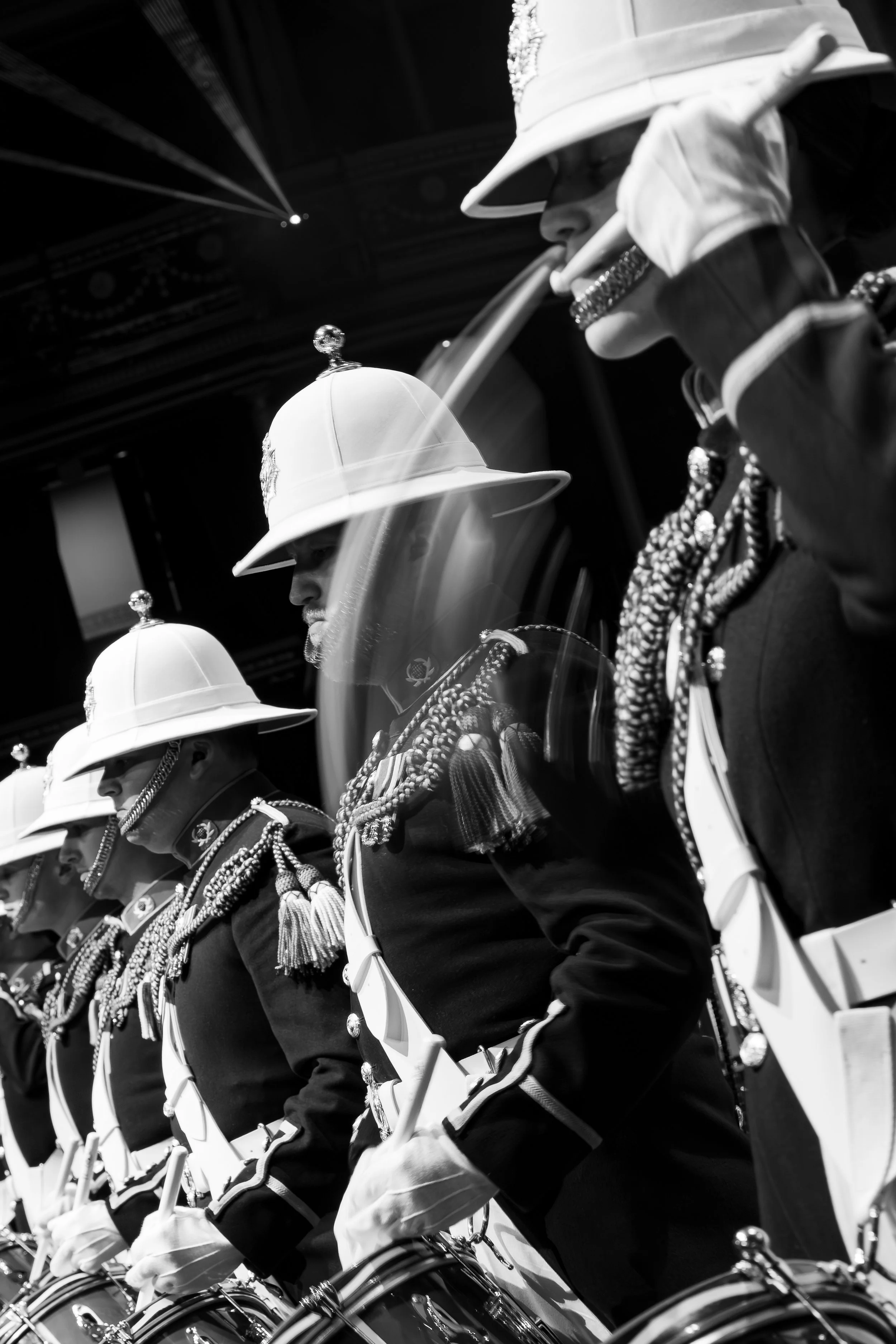 A black and white photo of soldiers in uniform, wearing ceremonial hats, standing in formation during a parade or military event.