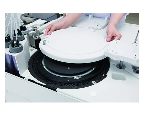 A person operating a medical laboratory test analyzer with various test tubes and equipment around.