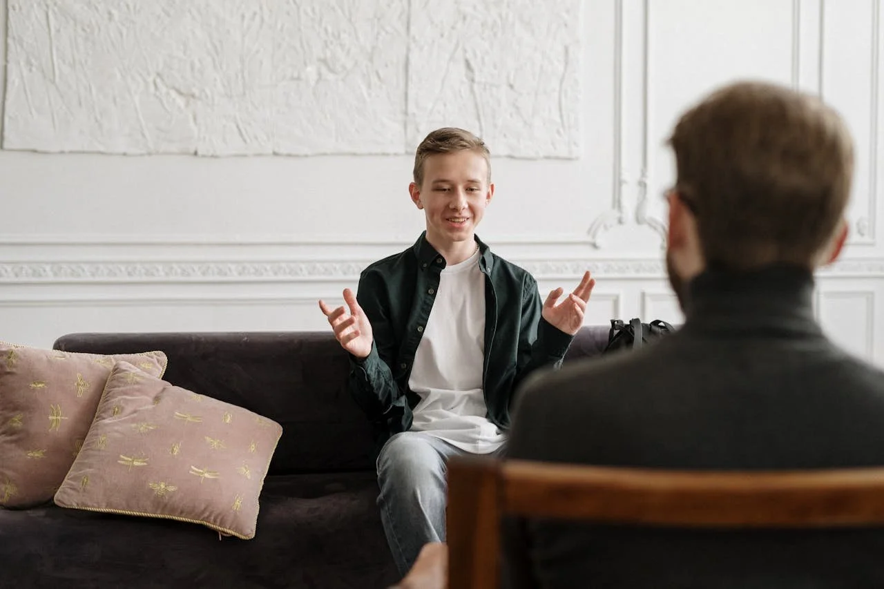 man-in-black-suit-jacket-sitting-on-brown-wooden-chair