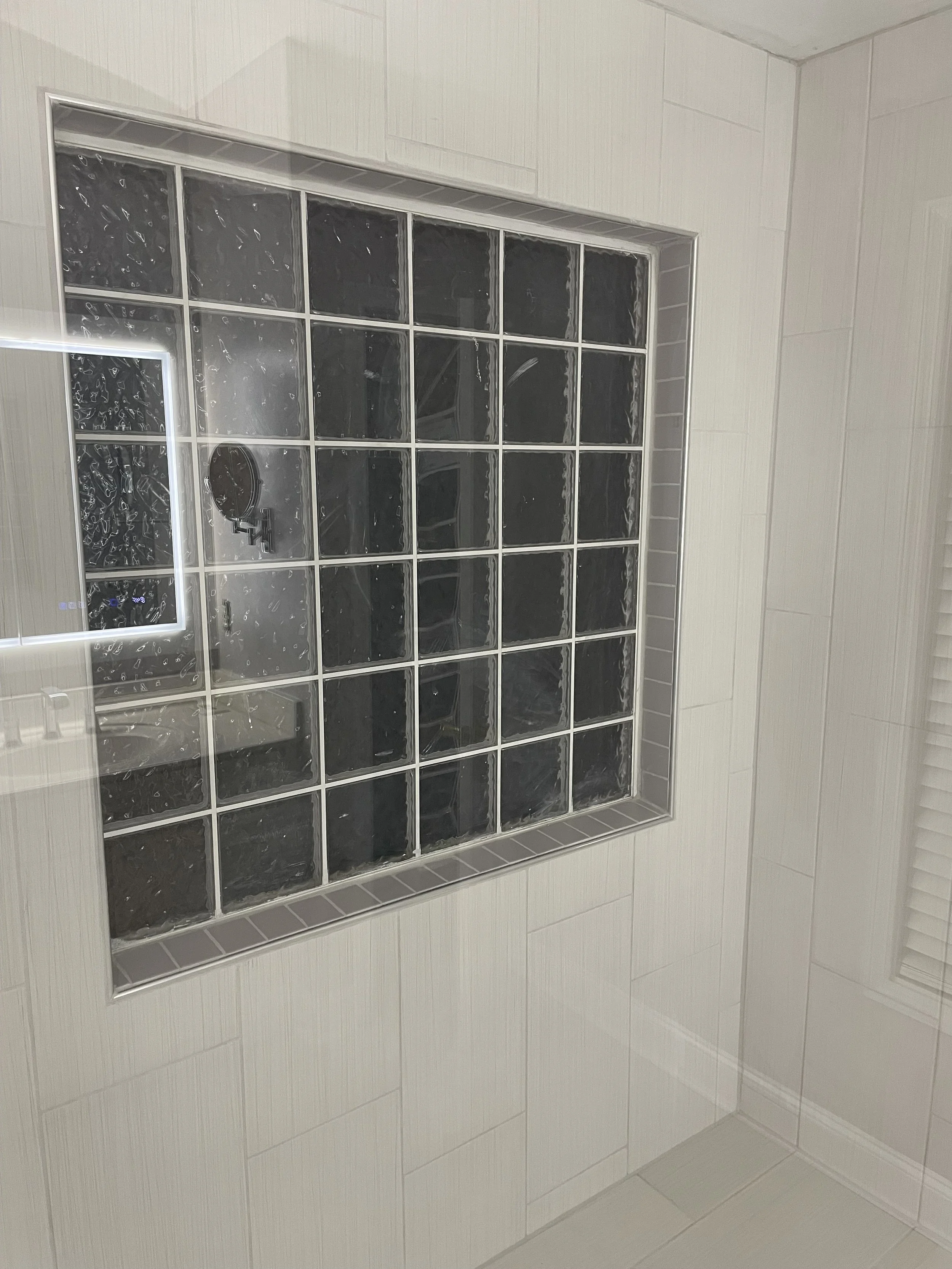 Bathroom shower with black glass blocks and beige tiles.