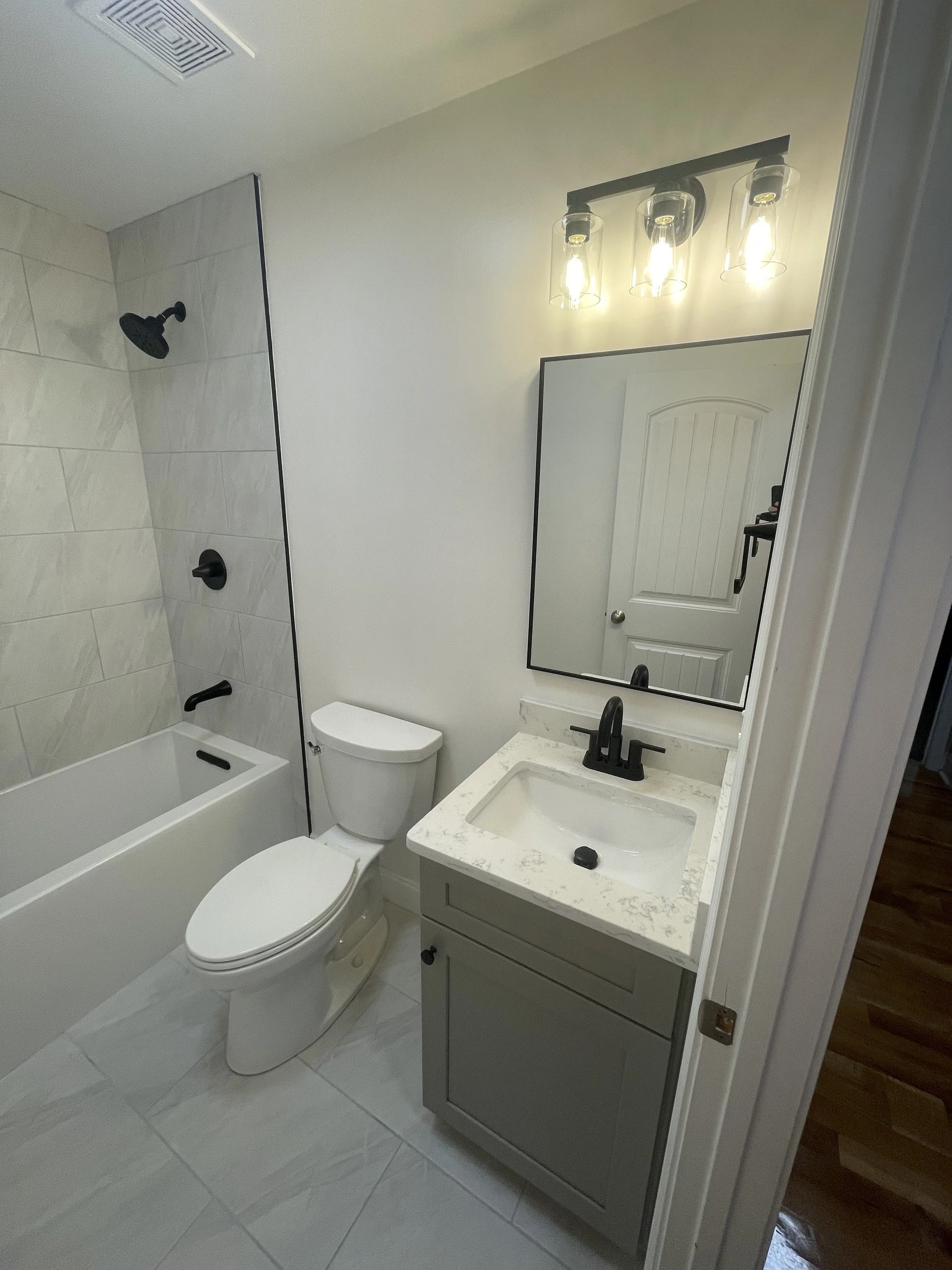 Bathroom with a shower, toilet, vanity with sink, mirror, and light fixture
