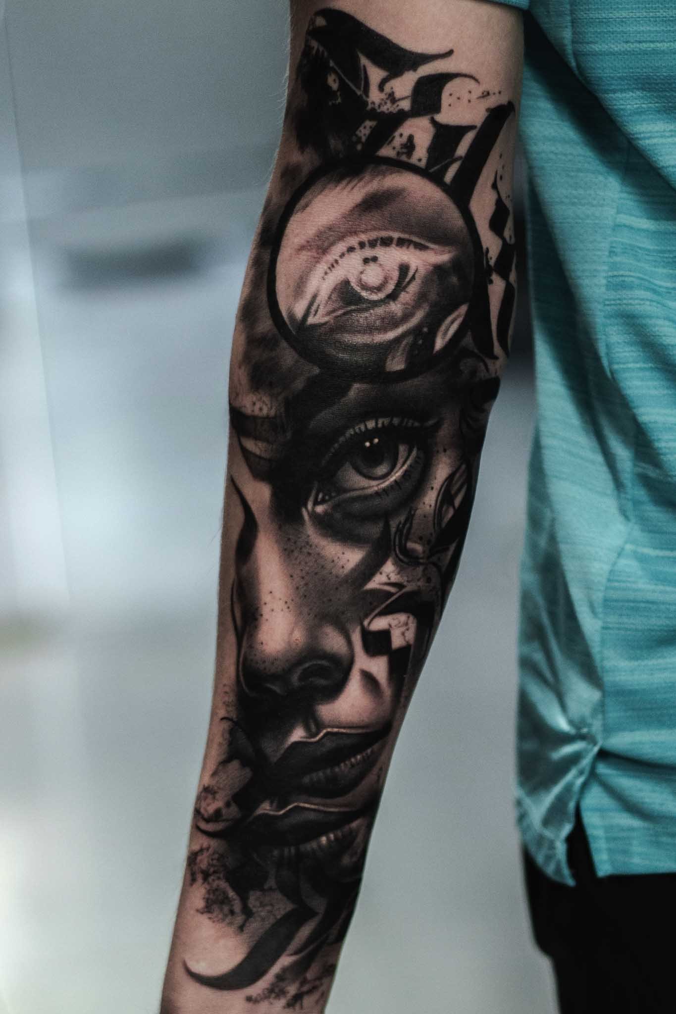 Black and grey surrealism woman's portrait with calligraphy writing on a forearm by Sheffield tattoo artist Steve Upton