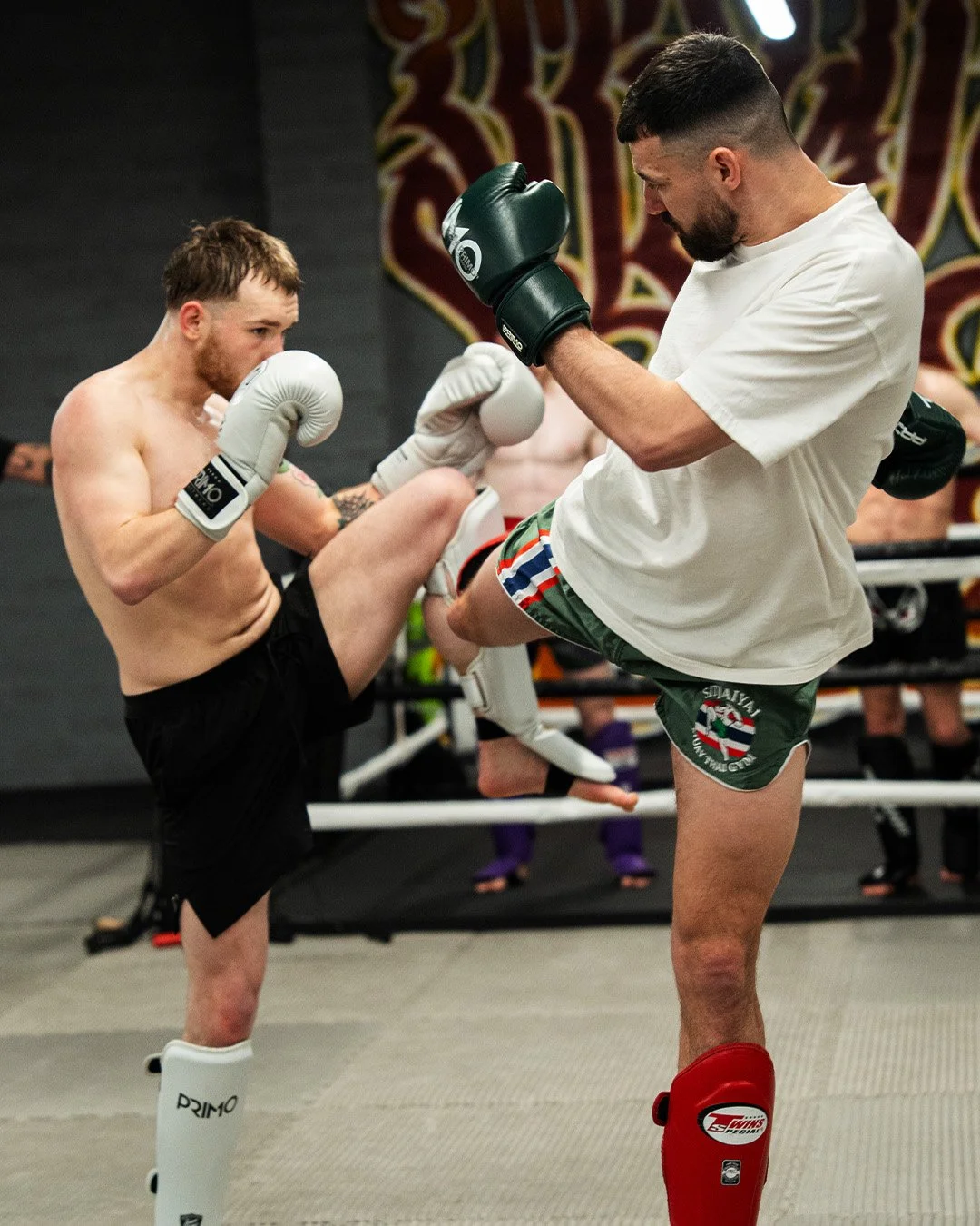 Two Muay Thai fighters sparring with simultaneous kicks during training at SitJaiYai gym, Worcester