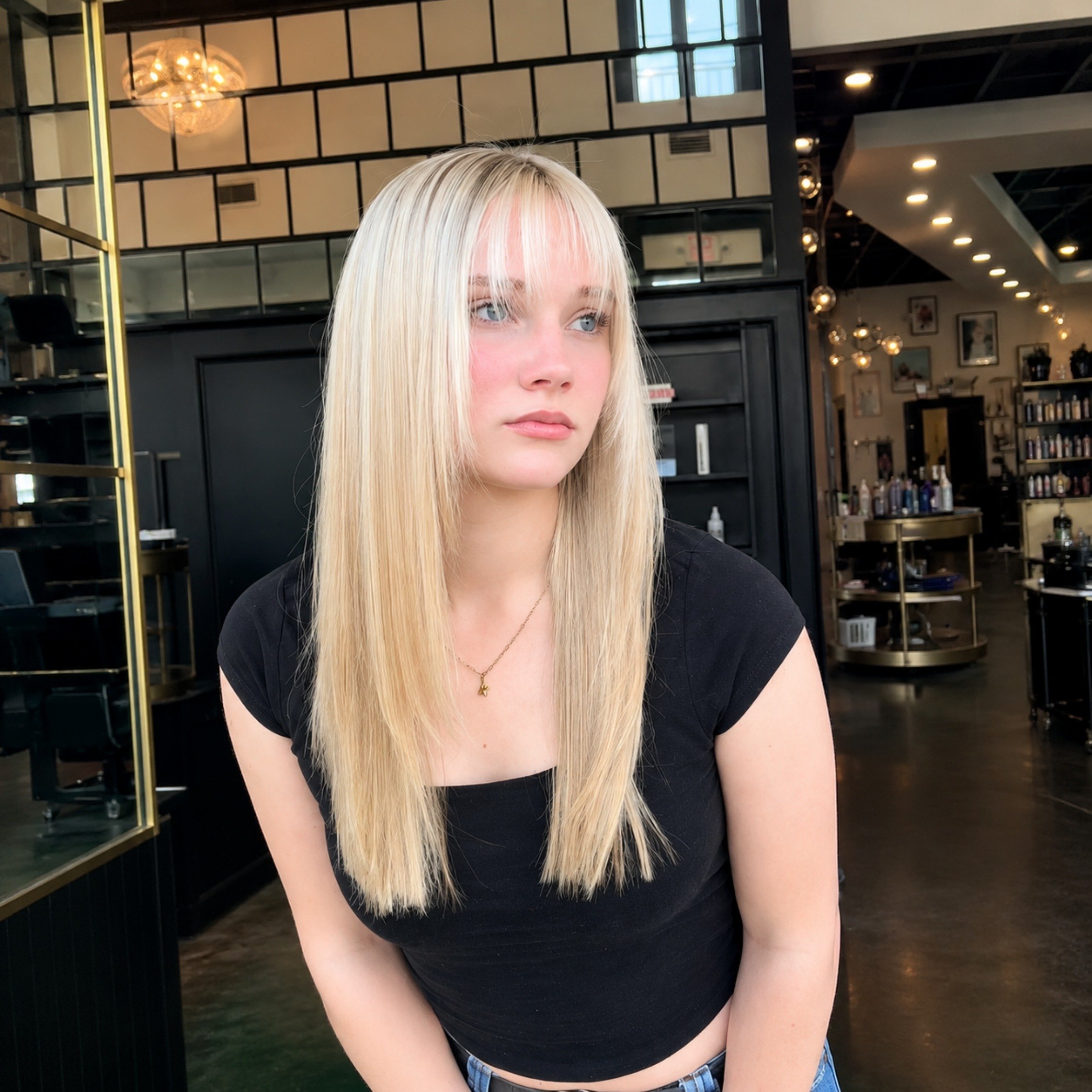 Long straight platinum blonde haircut with wispy bangs at Studio 285 hair salon in Evans, GA