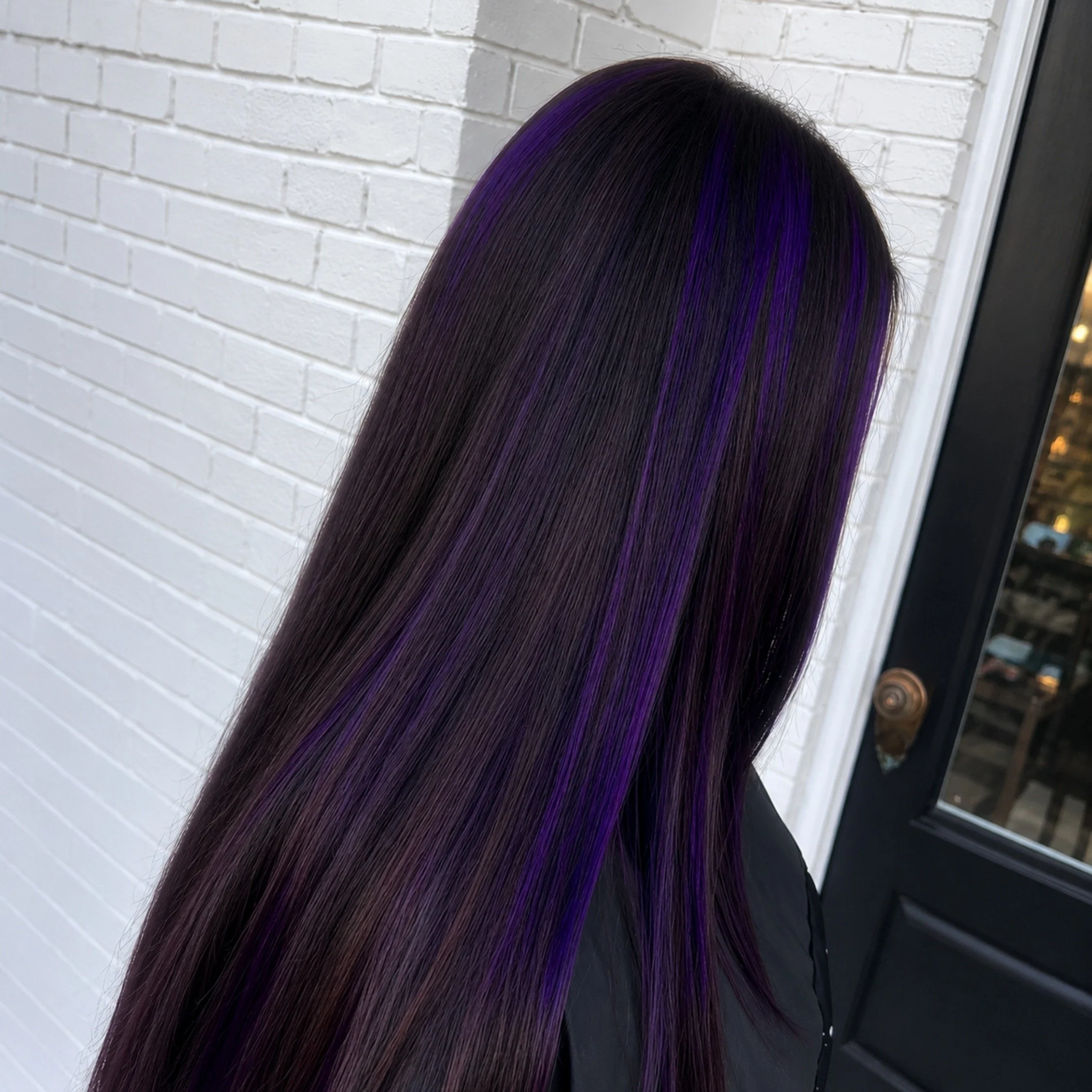 Long straight dark brunette hair with vivid purple highlights by a Studio 285 hair colorist