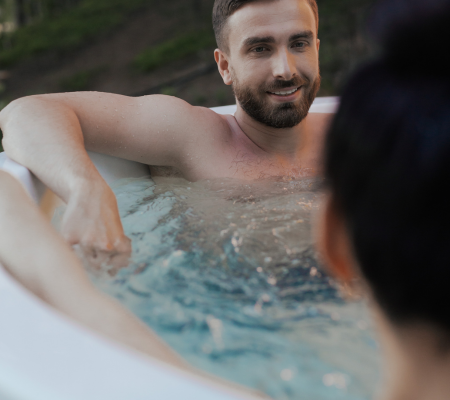 A man relaxing in a hot tub outdoors, smiling and enjoying the moment.