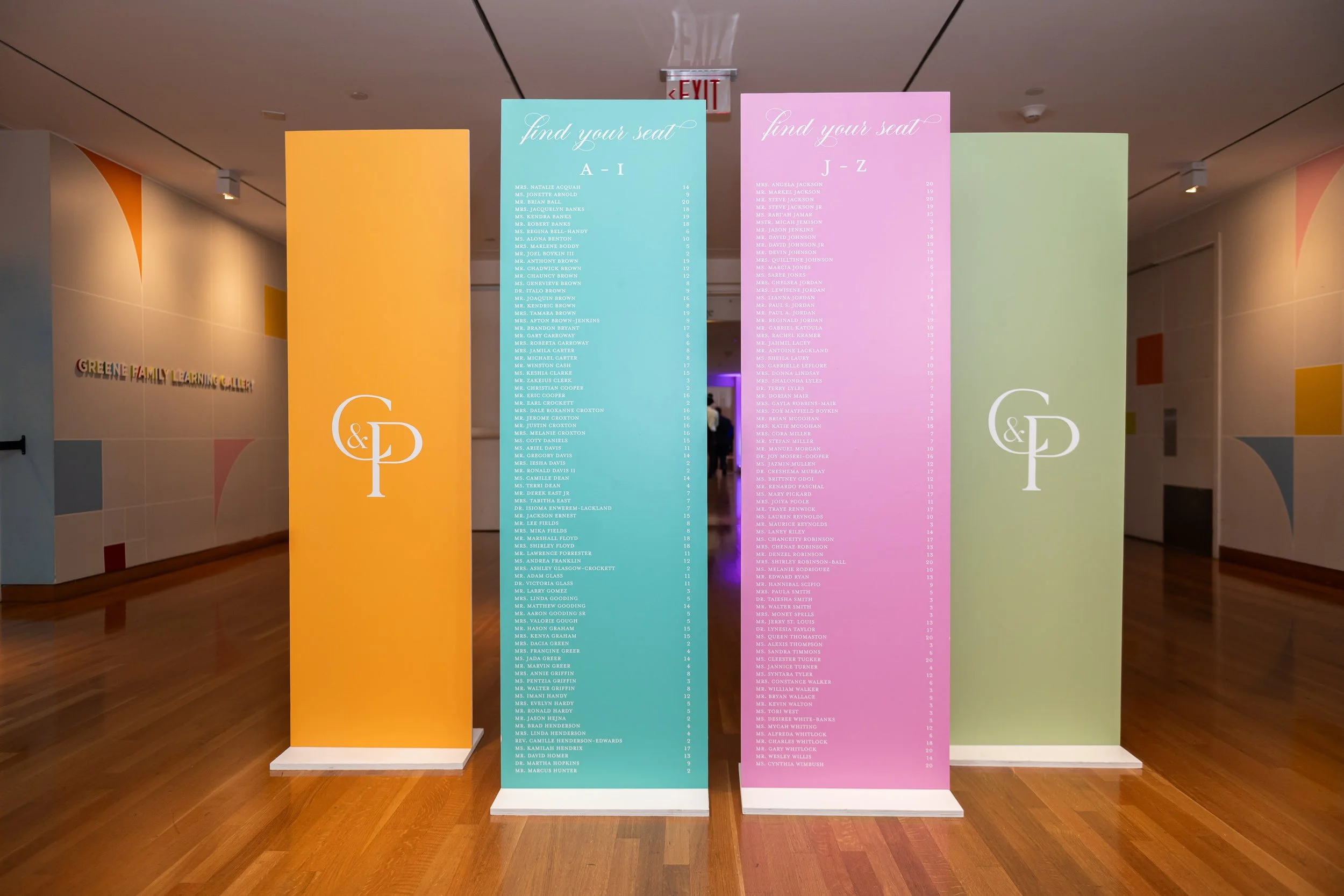 Colorful seat assignment signs with names and table numbers in a hallway of Greene Family Learning Gallery.