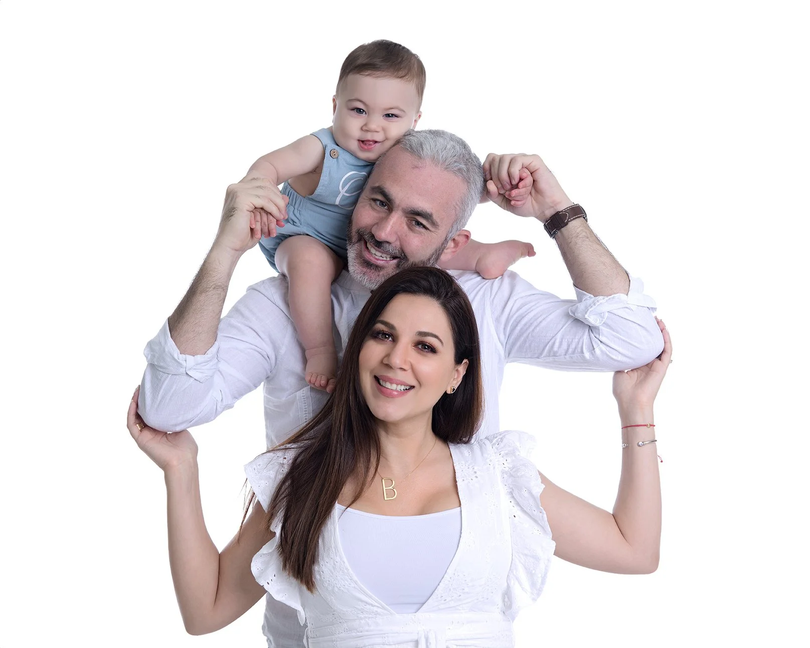 Happy family of three with a baby, smiling, posing together against a white background.