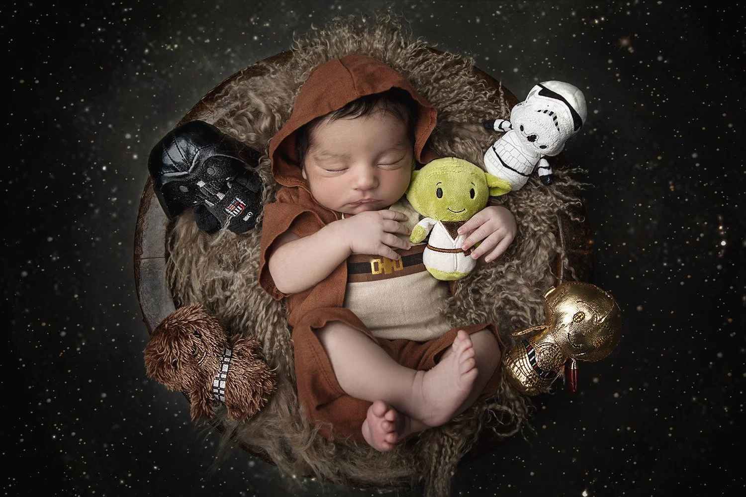 Sleeping baby dressed as a Star Wars character, surrounded by plush toys of Yoda, Darth Vader, a Stormtrooper, R2-D2, and Chewbacca, on a starry background.