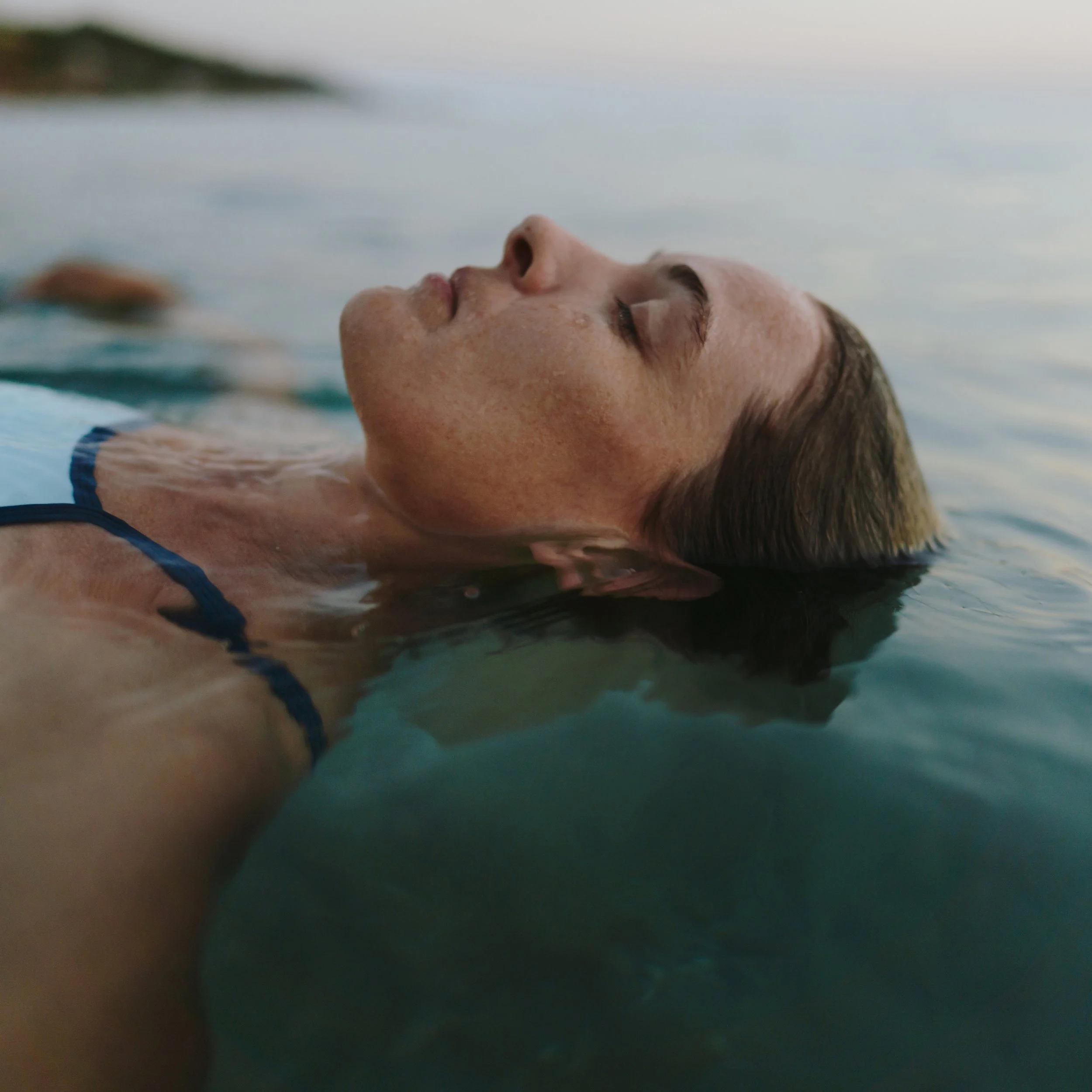 Menopausal woman floating in ocean with eyes closed