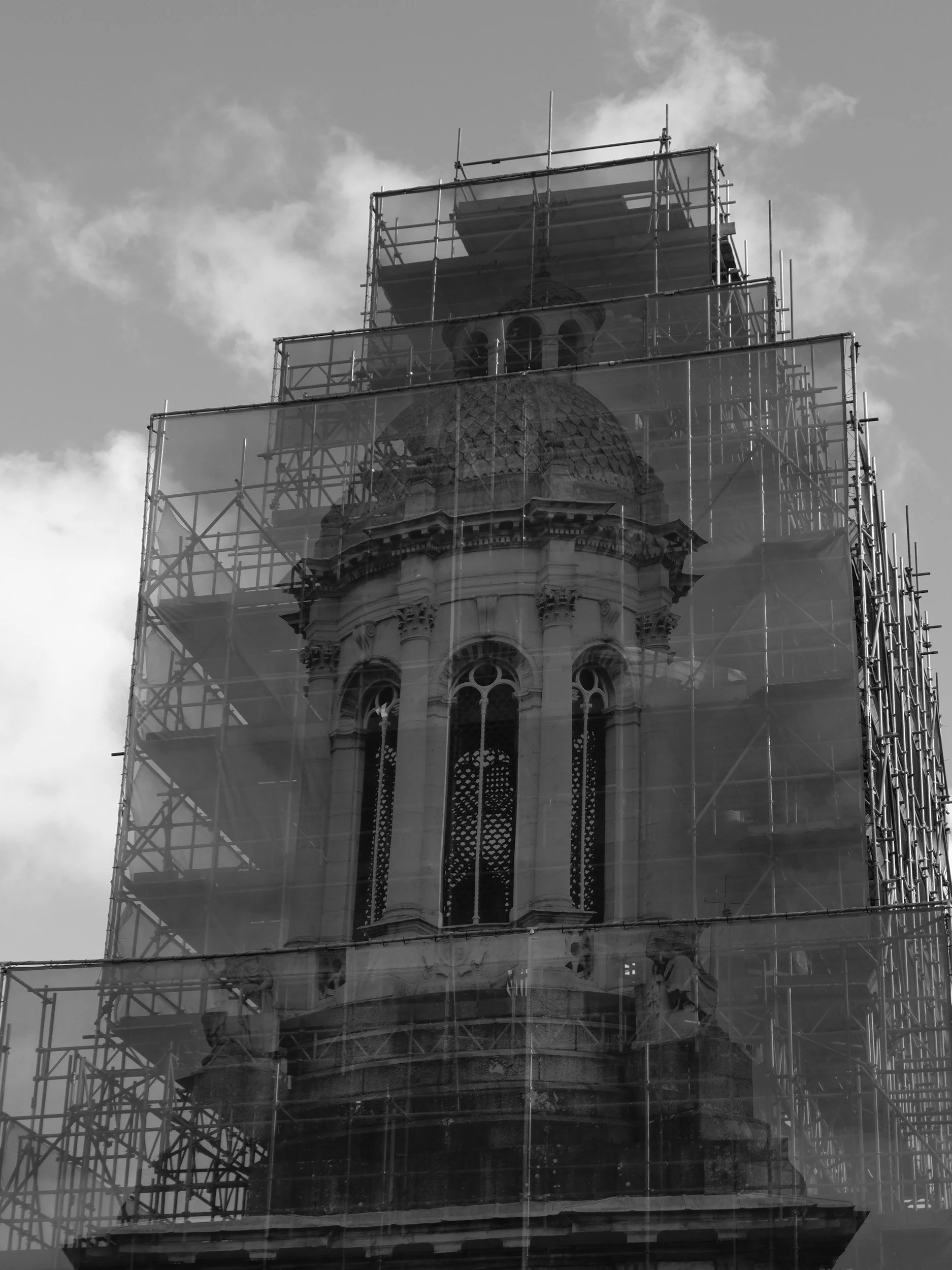 A historic building with a domed tower undergoing restoration, surrounded by scaffolding.