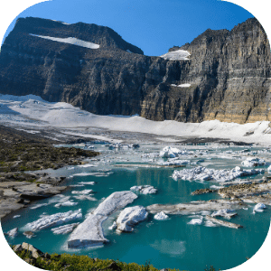 A mountain landscape with a glacier and a glacial lake with floating ice chunks.