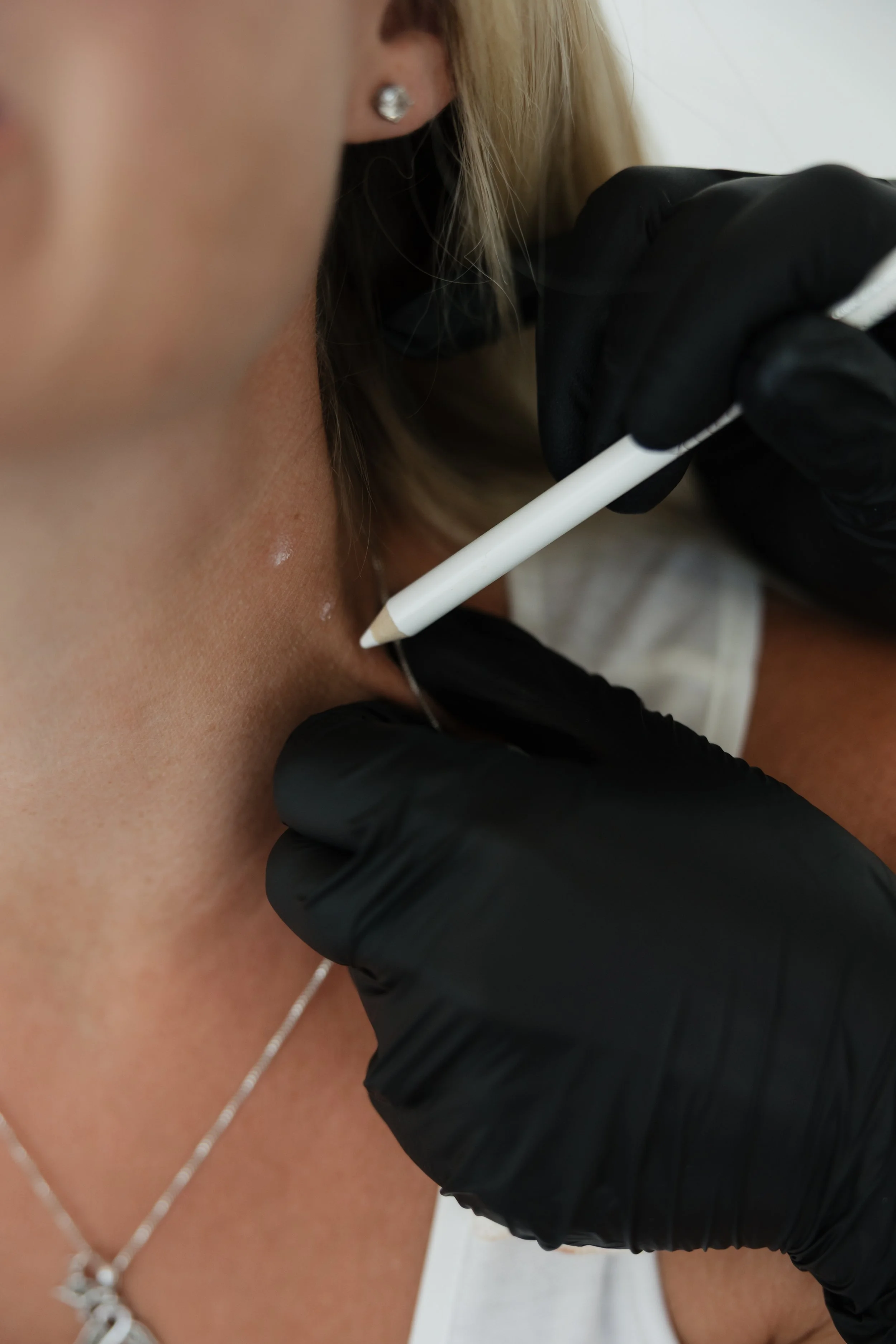 Close-up of a woman's neck and lower face with a neutral expression.