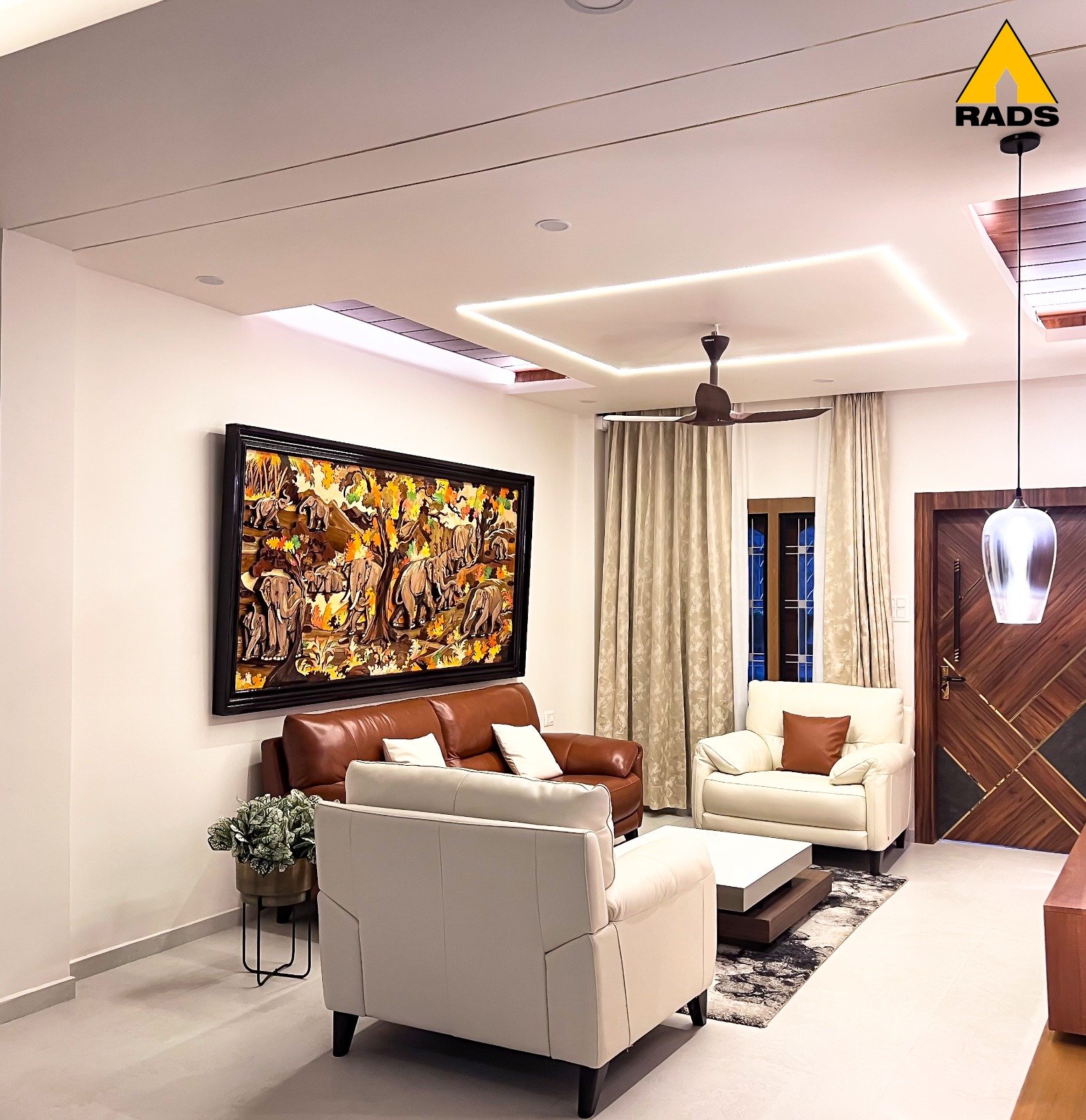 Modern living room interior in Guwahati with wooden and leather sofa seating, ethnic wall art, and ambient lighting.