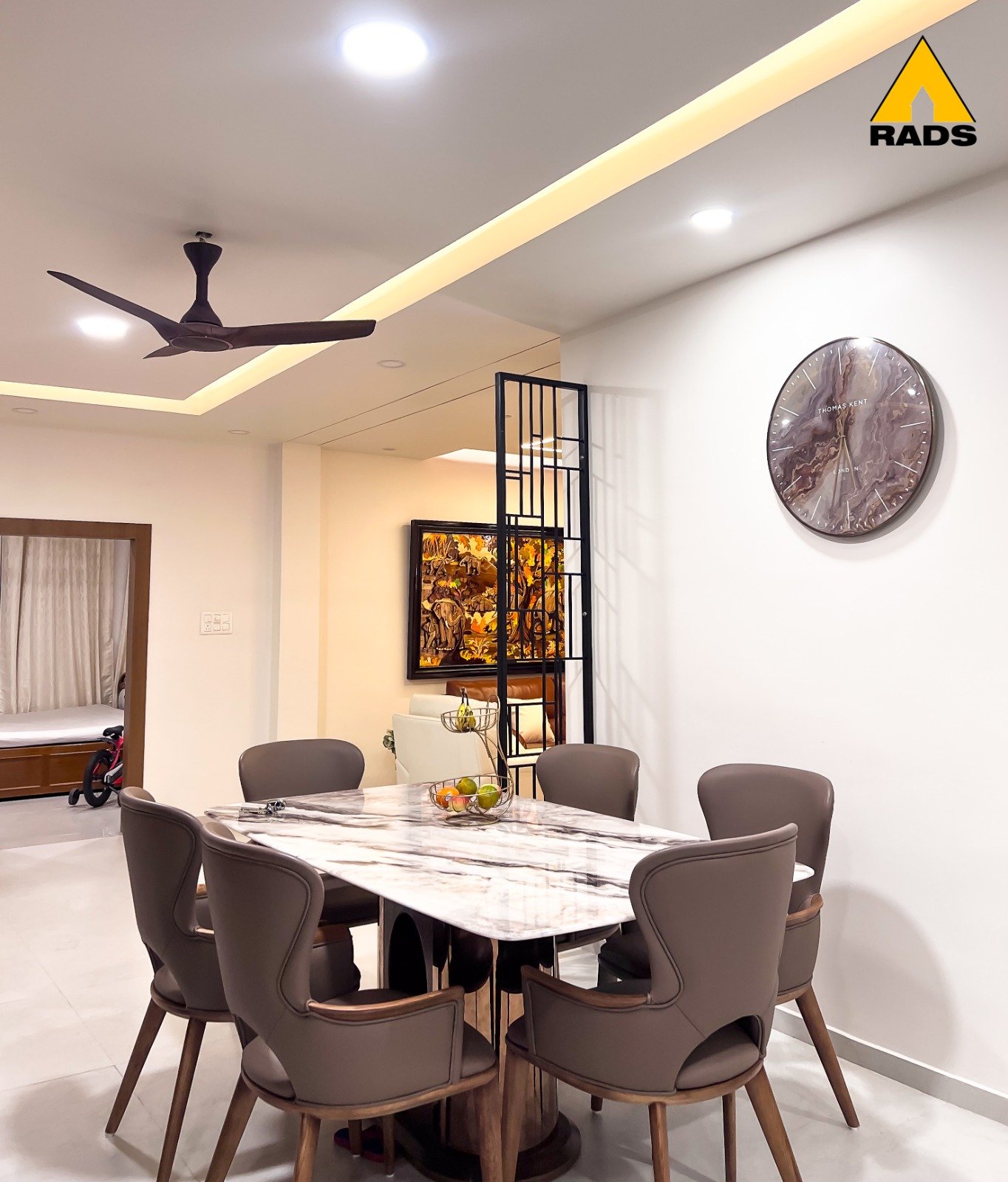 Elegant dining room interior with marble dining table, warm lighting, and false ceiling in Guwahati residence by RADS.