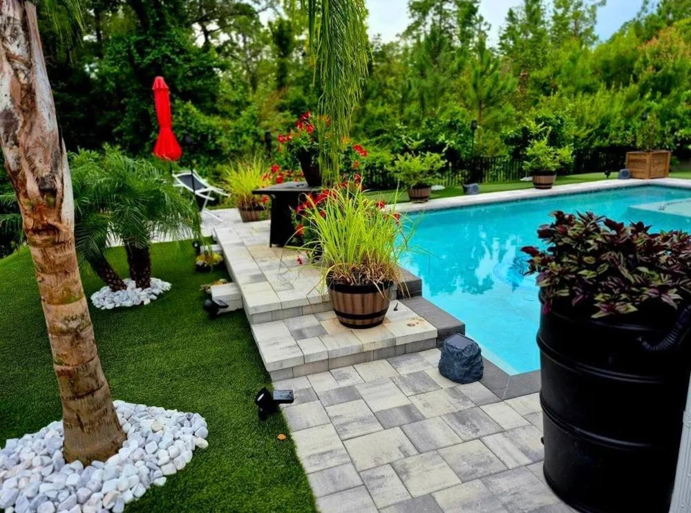 Purple marble pebbles and white stone accents installed around a tropical pool and paver patio