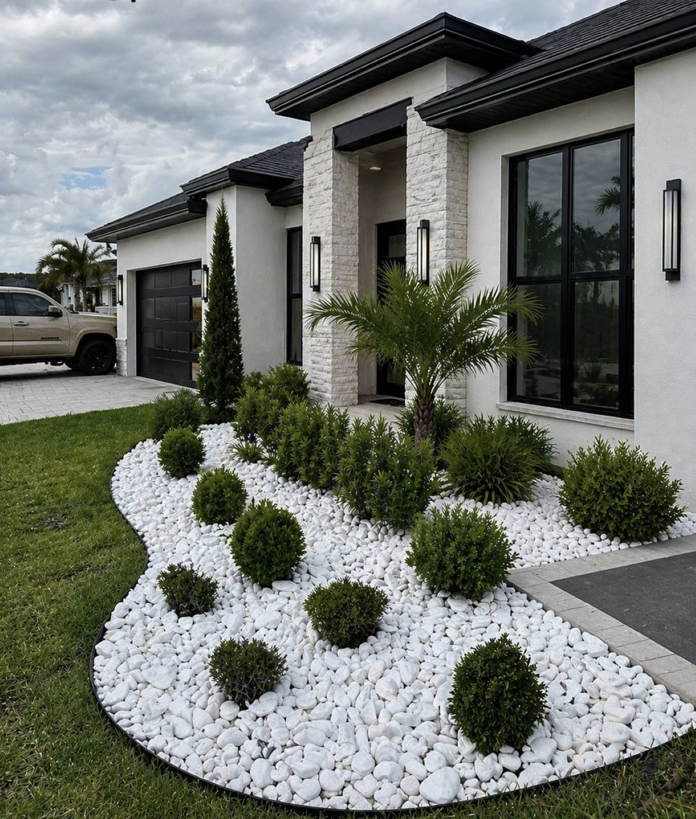 White marble pebbles forming a clean curved landscape bed around shrubs at a modern home