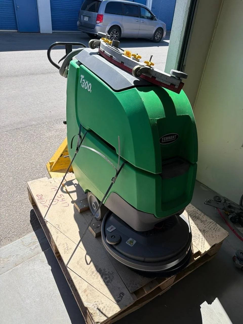 Green Tennant Floor Scrubber T300e on wooden pallet.
