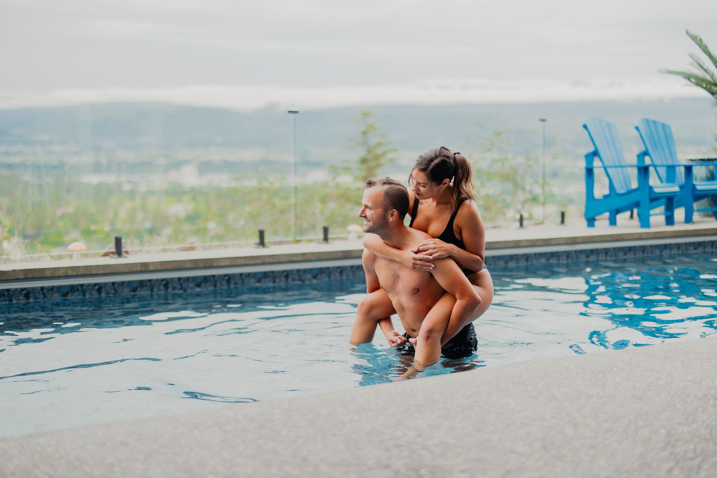 The Thera Retreat, a woman riding a man's back in a pool with beautiful scenery