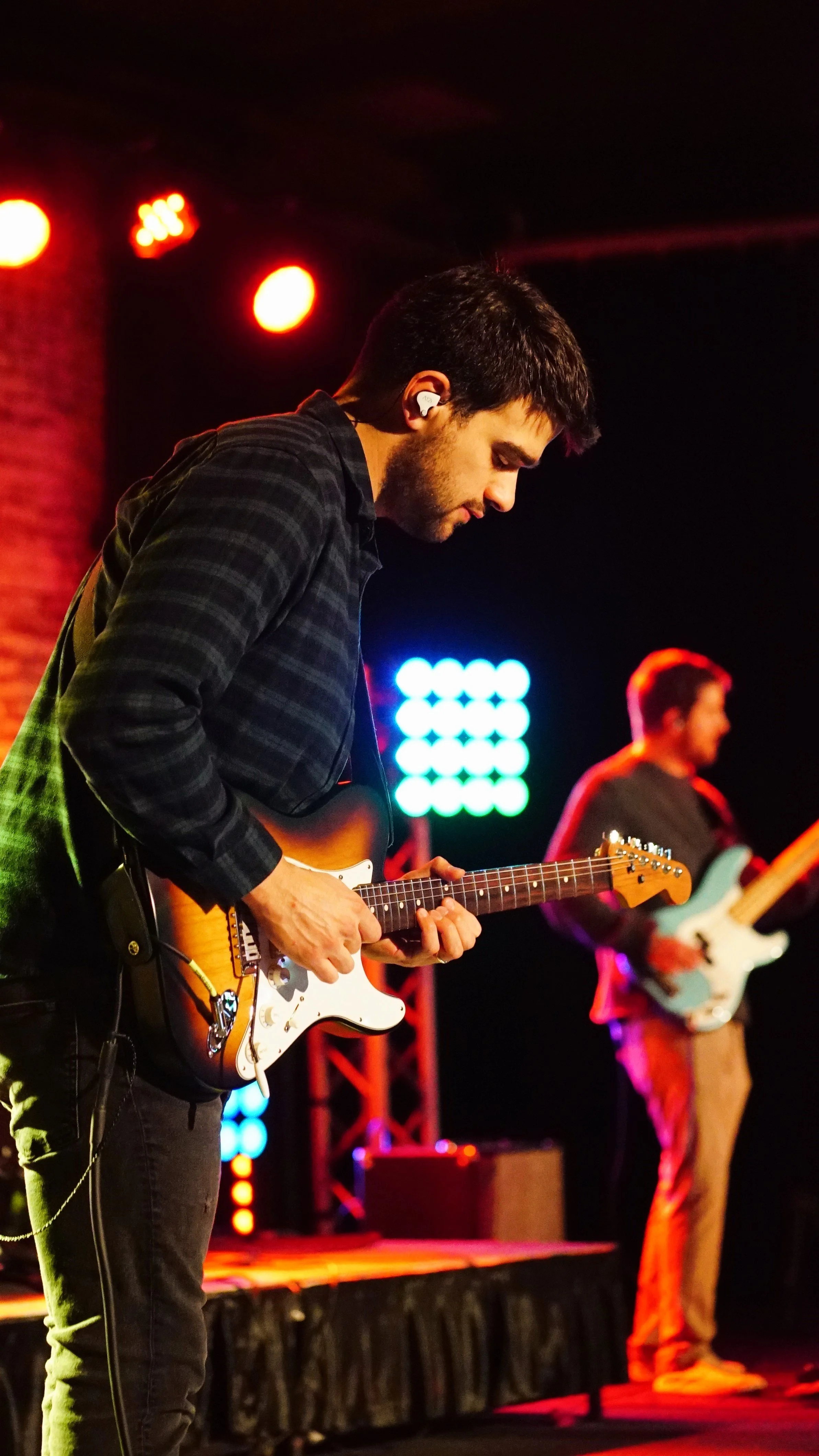 A person sitting cross-legged on a bed with pink pants, using a laptop, and holding a latte with latte art in a white mug.