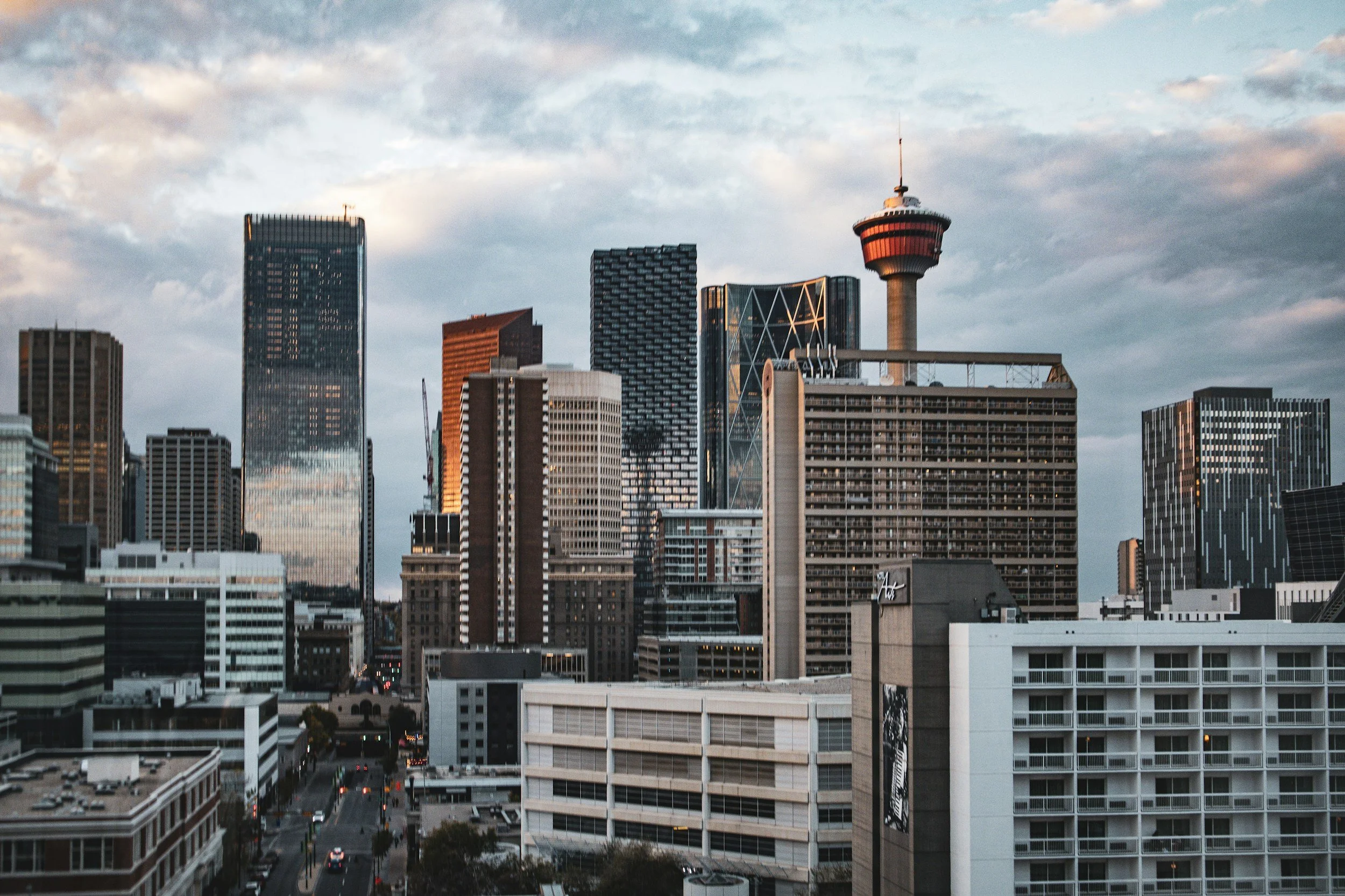 Sunset over a city skyline with tall office buildings, streets, and a church in the foreground.