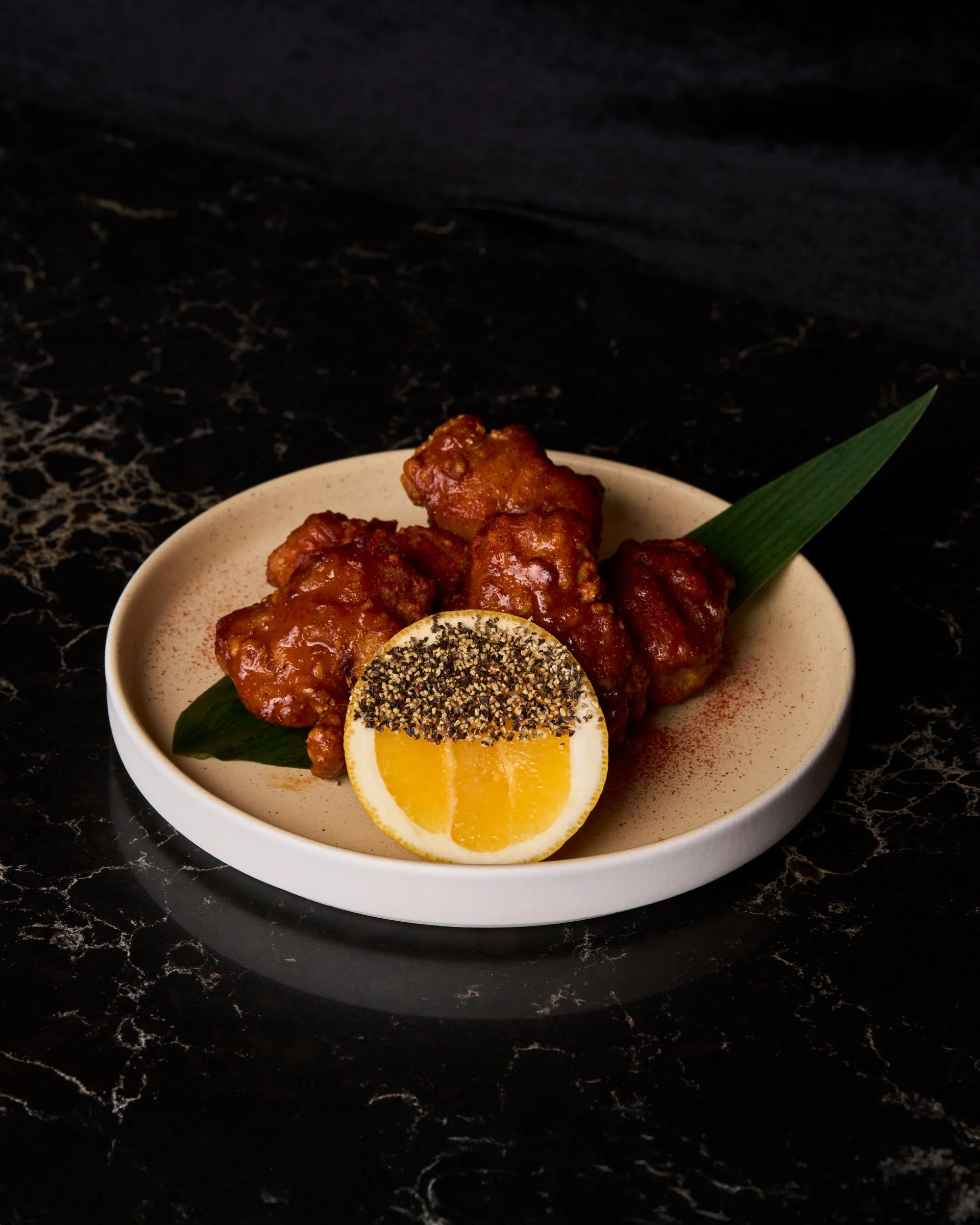 Fried chicken wings with lemon wedge and black pepper on a white plate